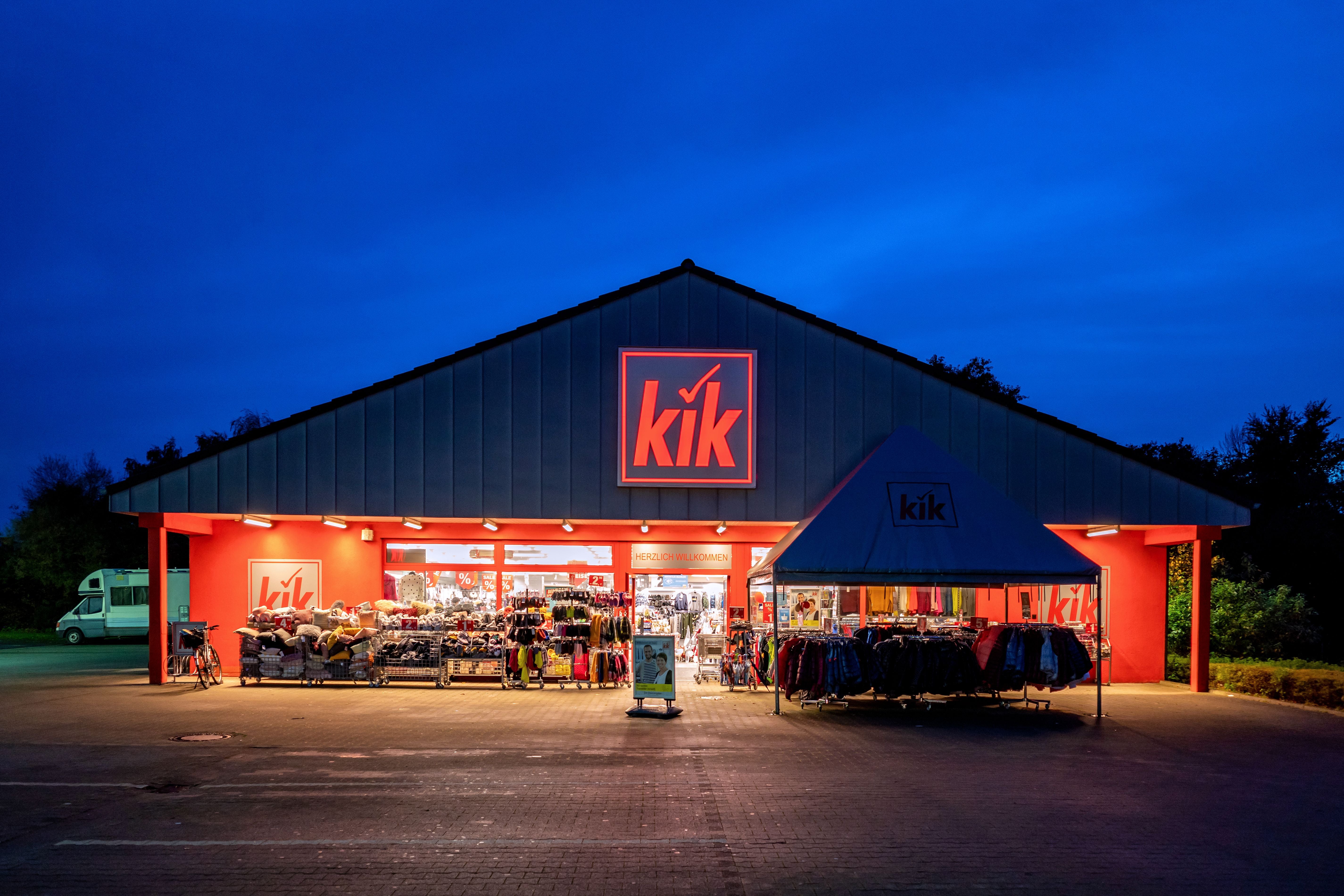 Beleuchtete KiK-Filiale mit Kleidungsauslage am Abend in Cuxhaven, Deutschland.