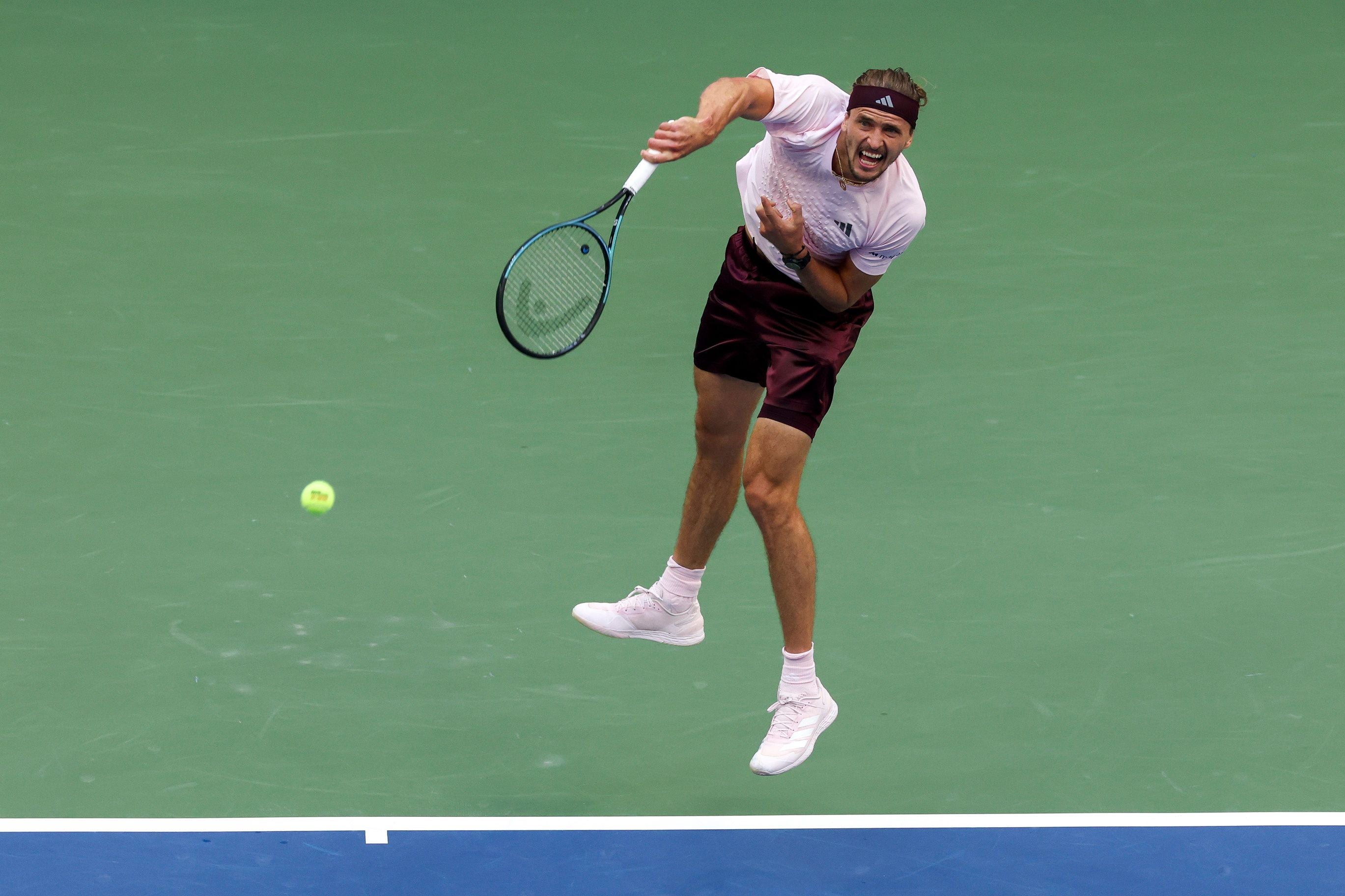 Ein Tennisspieler schlägt auf einem Hartplatz einen Aufschlag während eines Spiels.