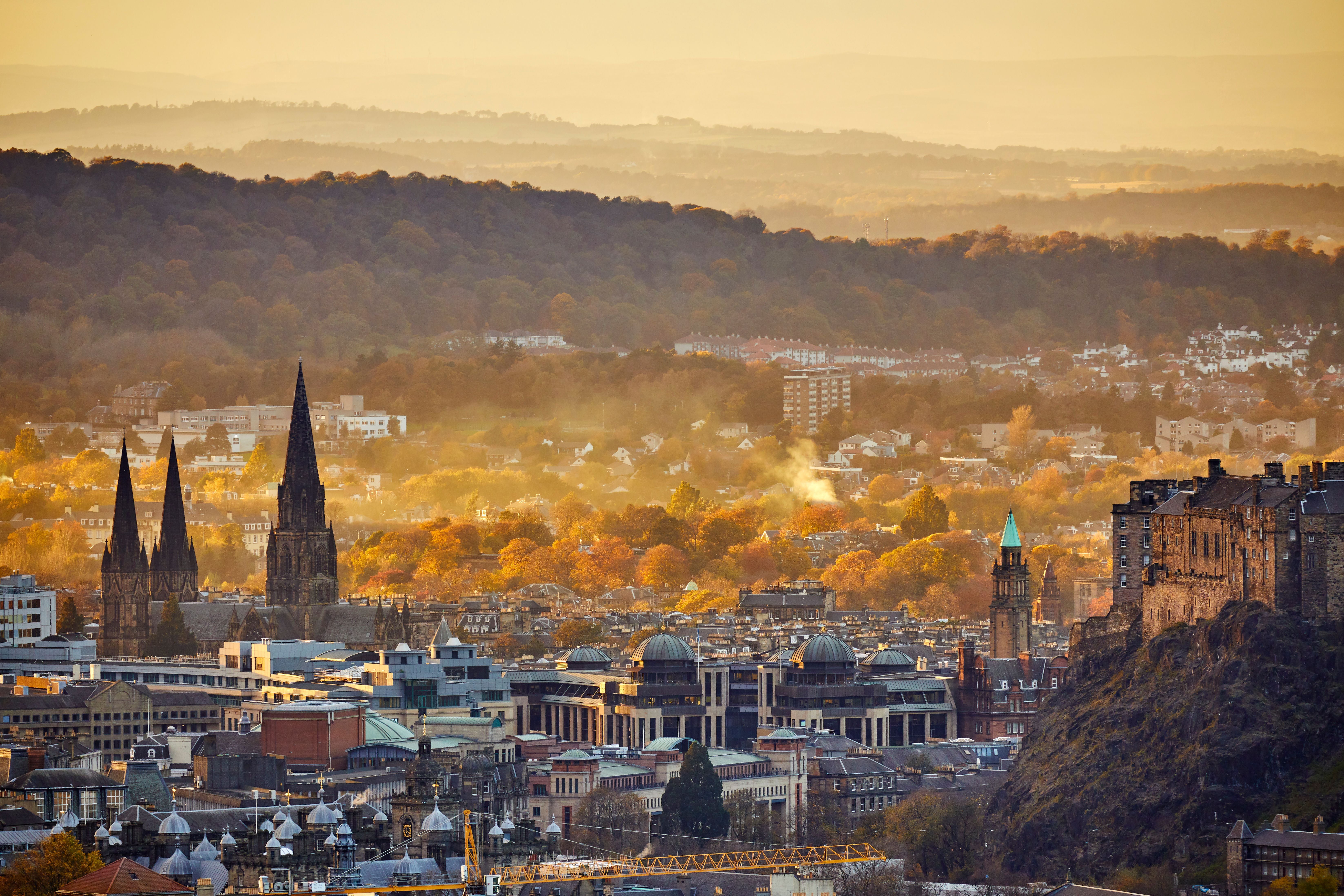 Blick auf Edinburgh im Herbst mit Stadtgebäuden und Edinburgh Castle rechts im Bild.