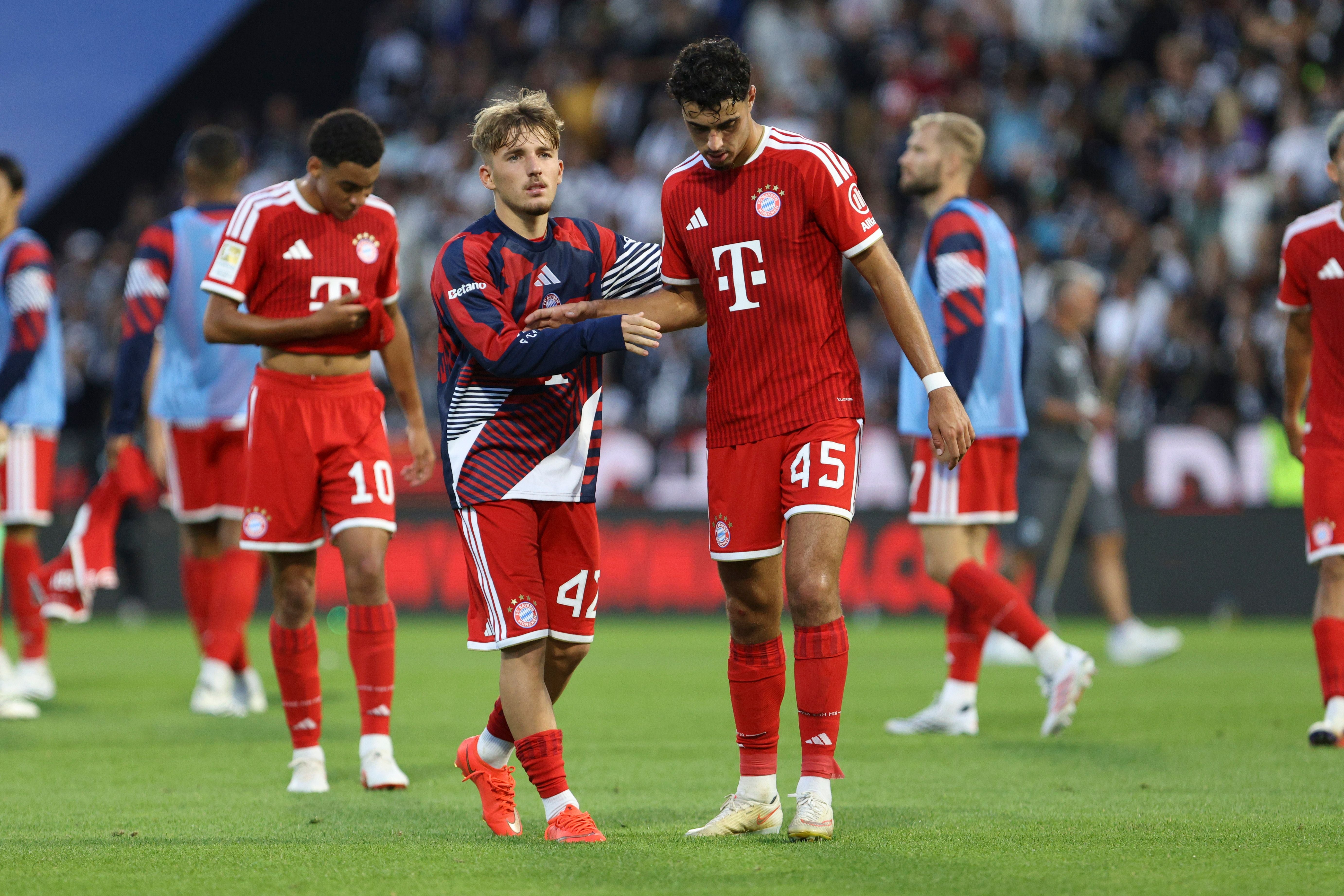 Zwei Bayern-Spieler schütteln sich nach dem Spiel traurig die Hand auf dem Fußballfeld.