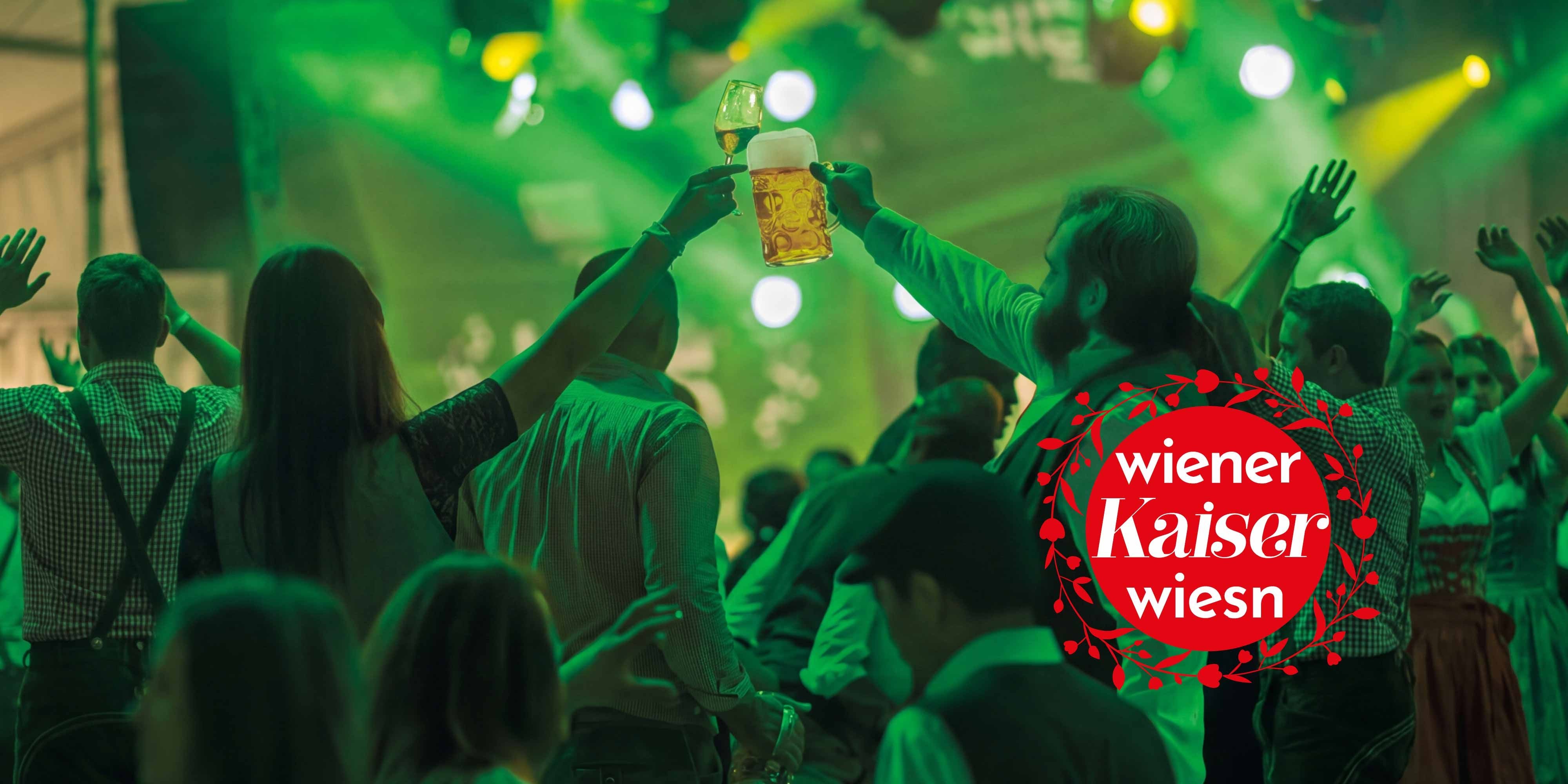 Menschen feiern, stoßen mit Bier und Wein an, im Hintergrund grüne Lichter, Wiener Kaiser Wiesn Logo.