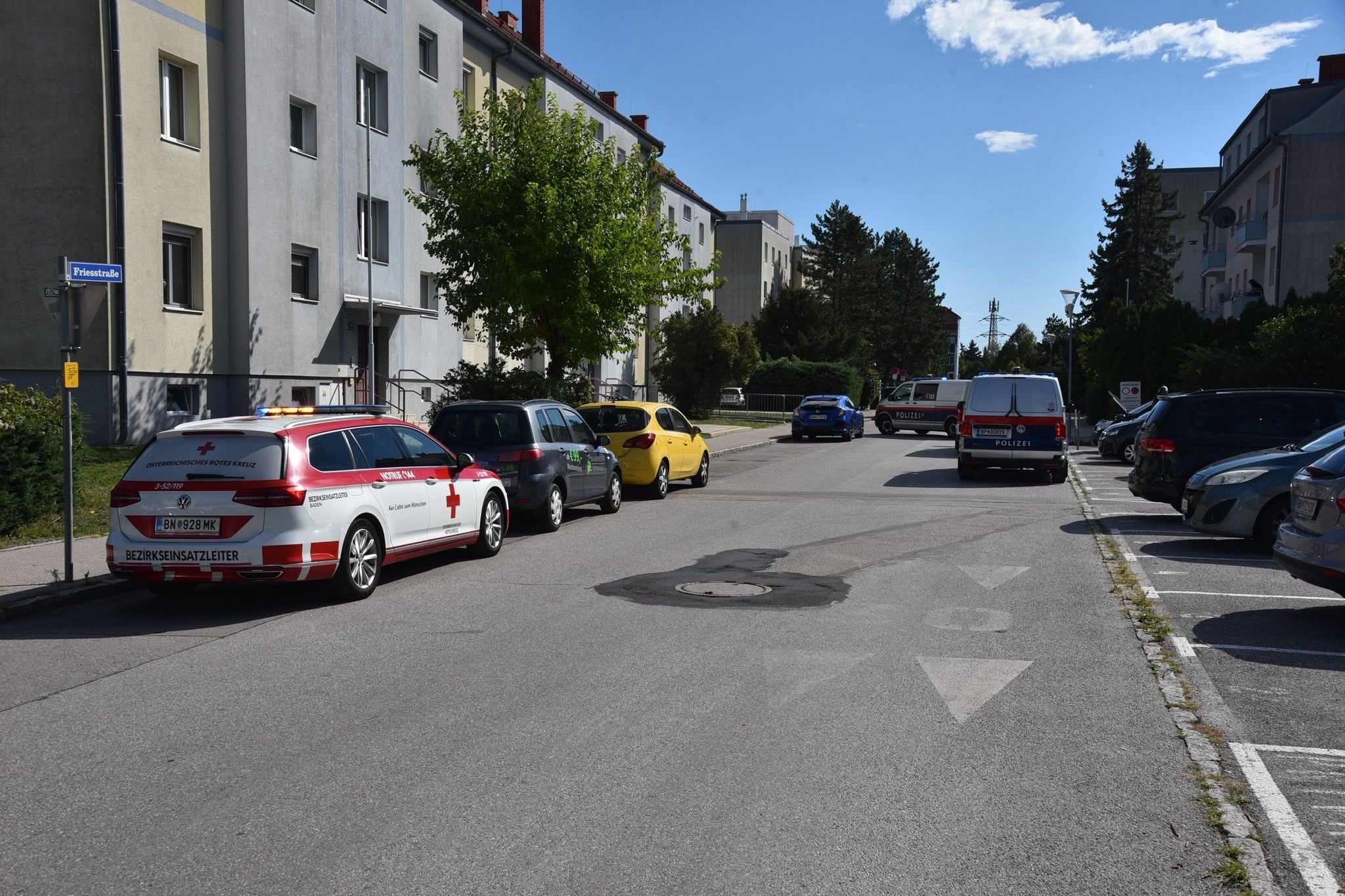 Polizei- und Rettungswagen parken in einer Wohnstraße in Bad Vöslau bei sonnigem Wetter.