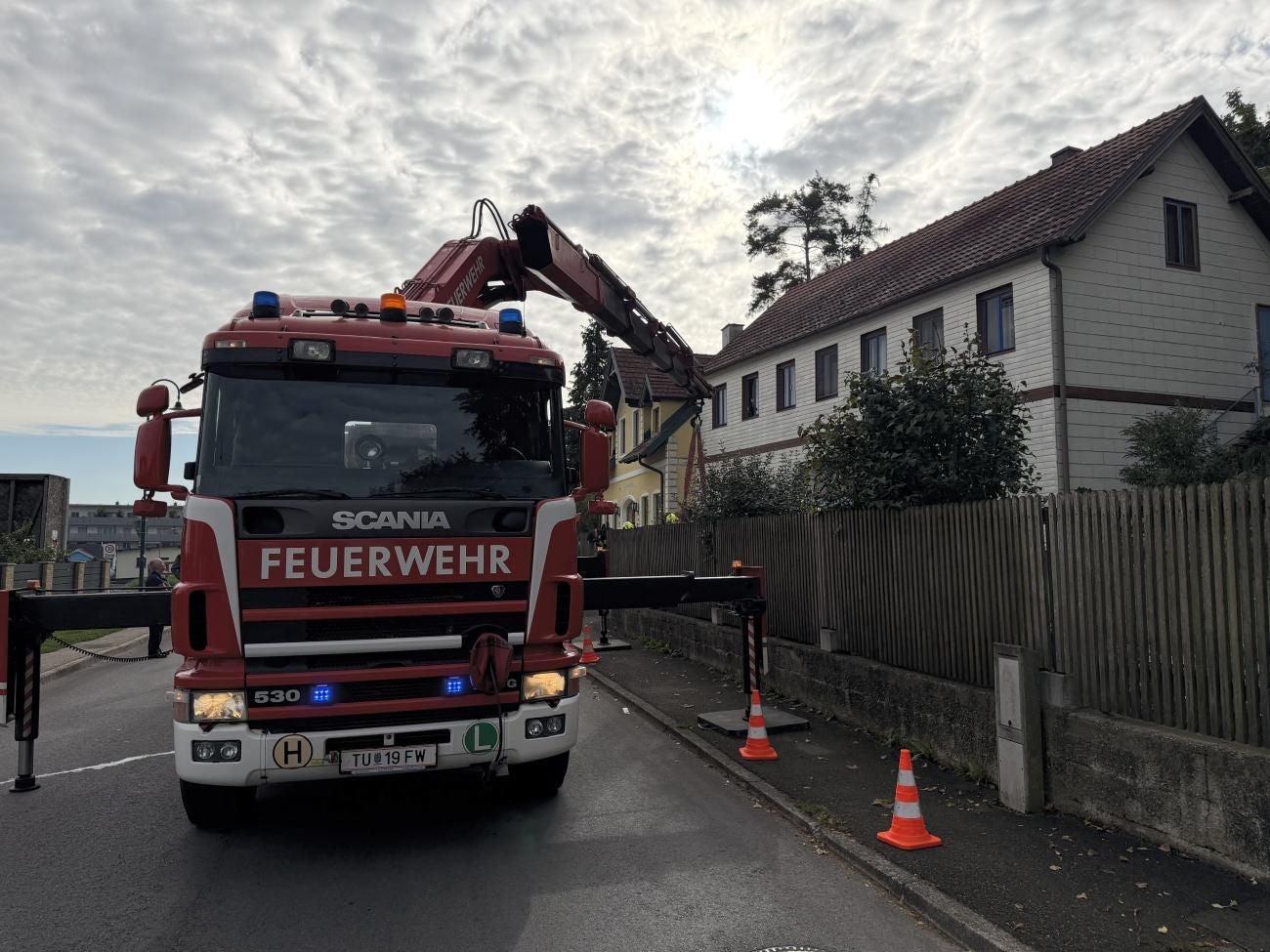 Ein Feuerwehrfahrzeug mit Kran steht vor einem Haus, Einsatz wegen totem Pferd am Balkon.