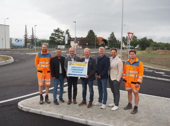 Sieben Personen stehen auf einer Verkehrsinsel an einem neuen Kreisverkehr in Leobersdorf.