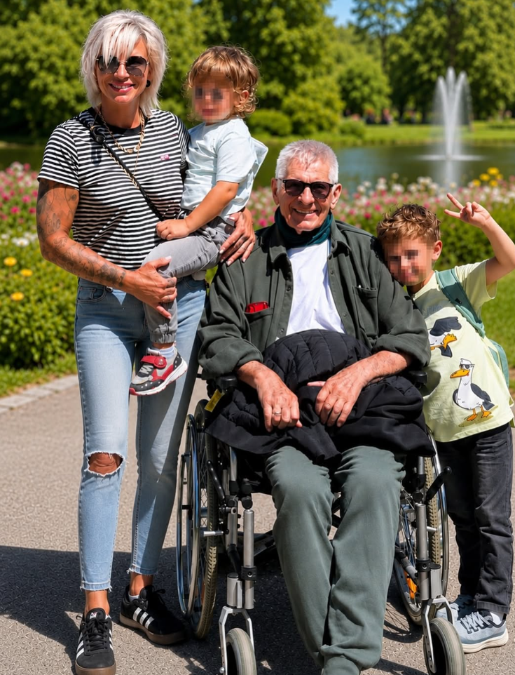 Eine Familie mit zwei Kindern und einem Mann im Rollstuhl posiert lächelnd im sonnigen Park.