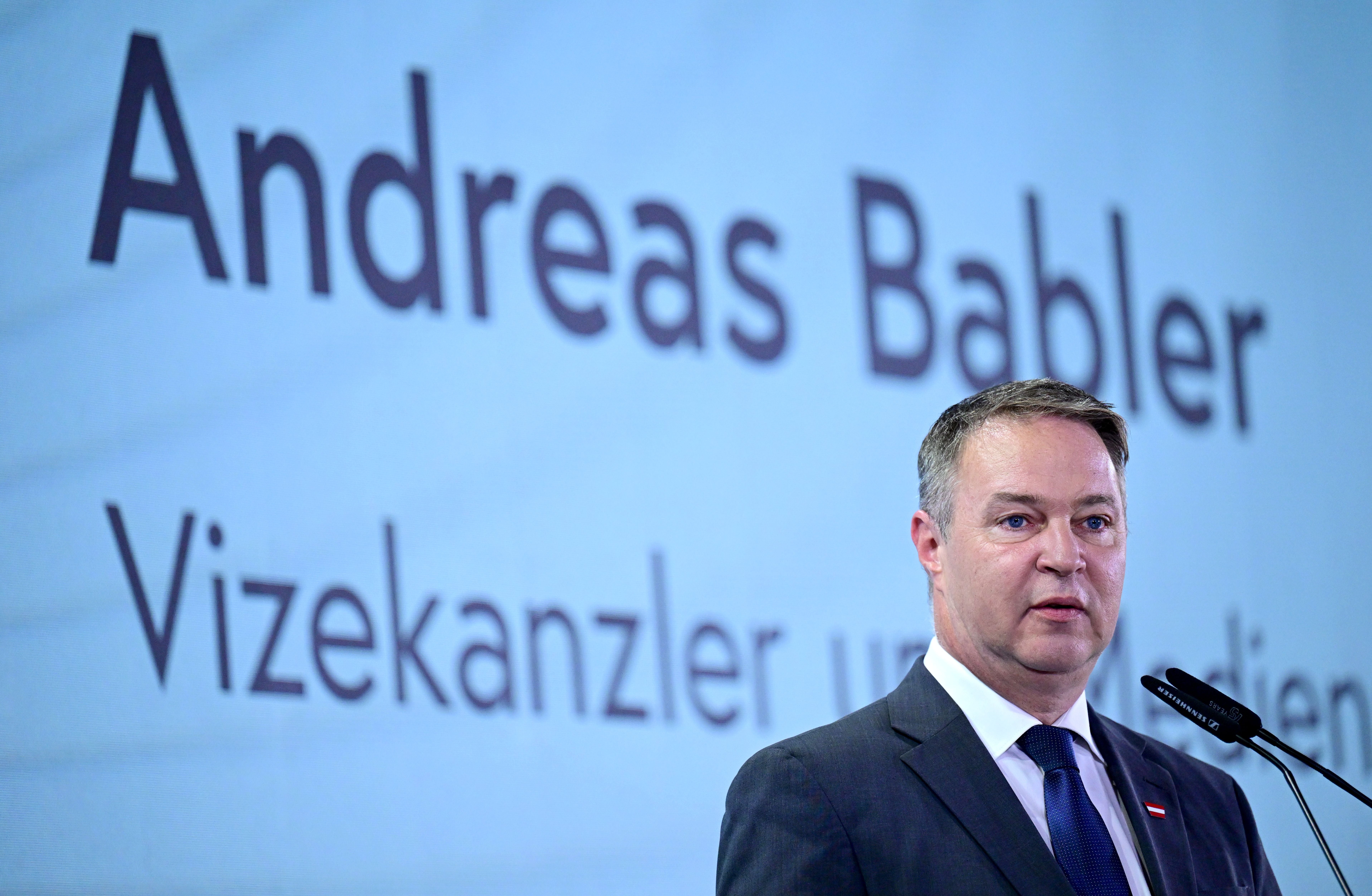 Ein Mann im Anzug spricht am Rednerpult; im Hintergrund steht "Andreas Babler".