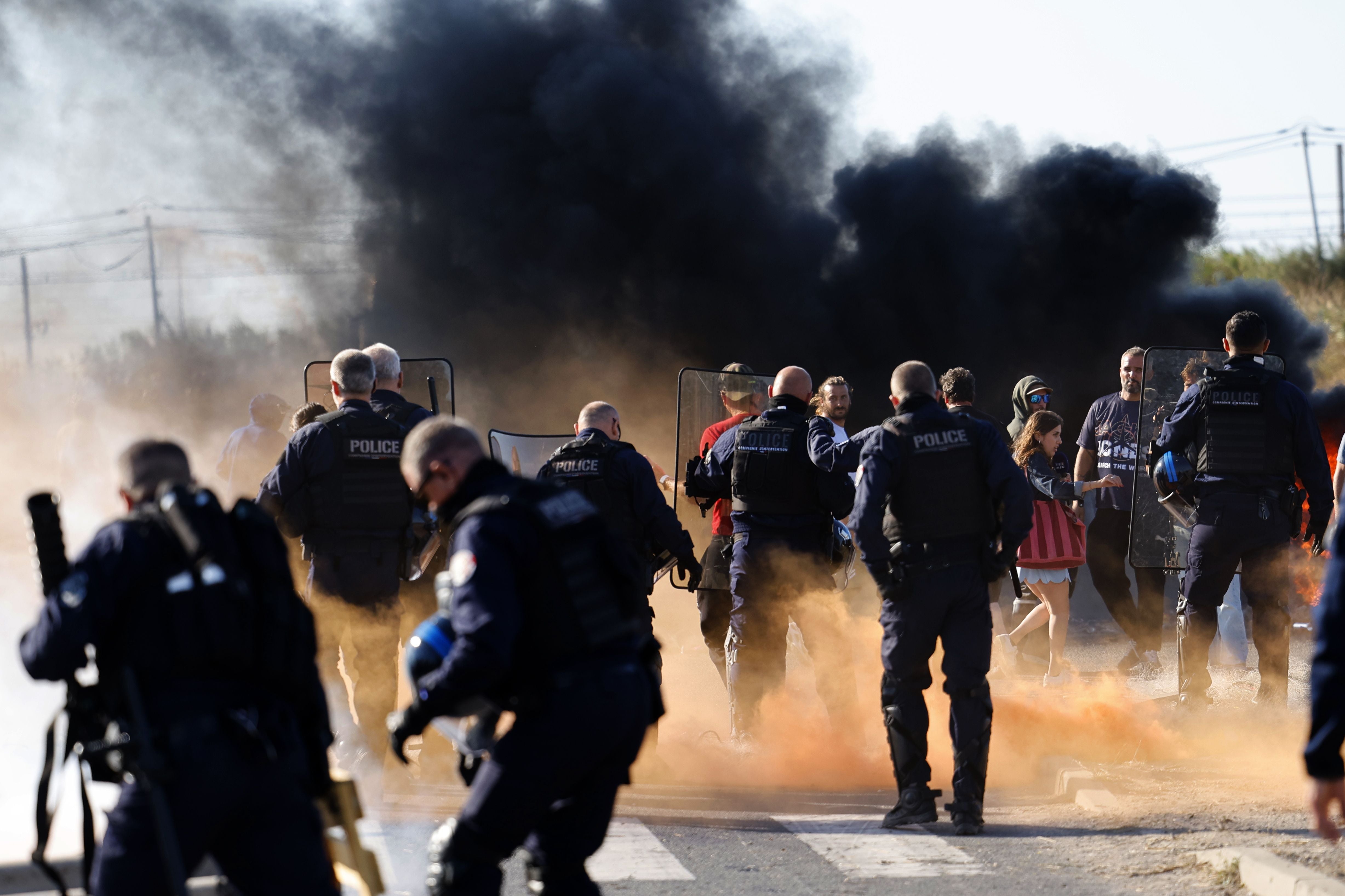 Polizisten und Demonstranten stehen sich vor einer Rauchwolke bei einem Streik in Südfrankreich gegenüber.