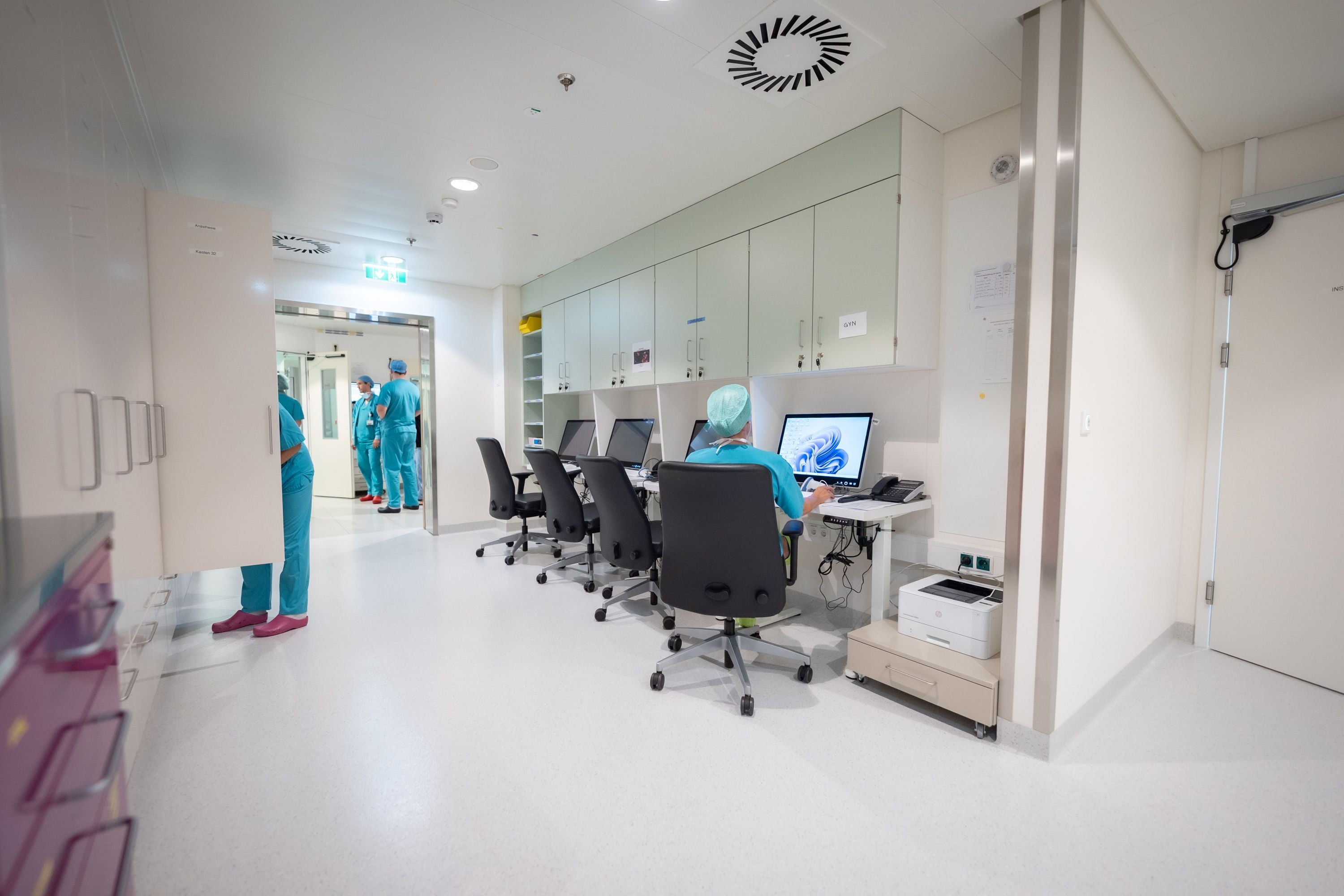 Medizinisches Personal arbeitet an Computern in einem modernen Krankenhausflur.