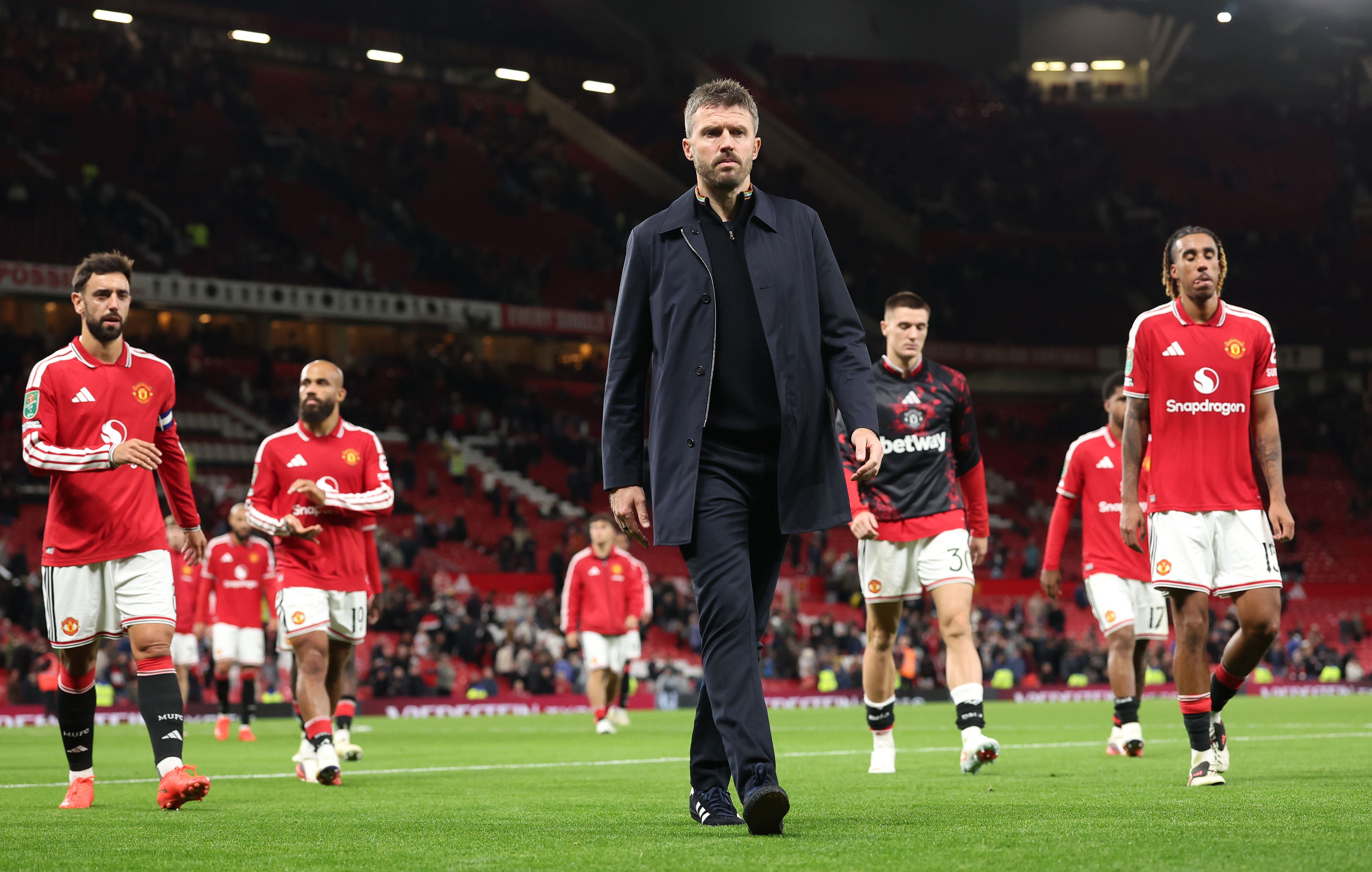 Michael Carrick geht mit ernster Miene über den Rasen im Old Trafford, während die enttäuschten Spieler von Manchester United im Hintergrund den Platz verlassen.