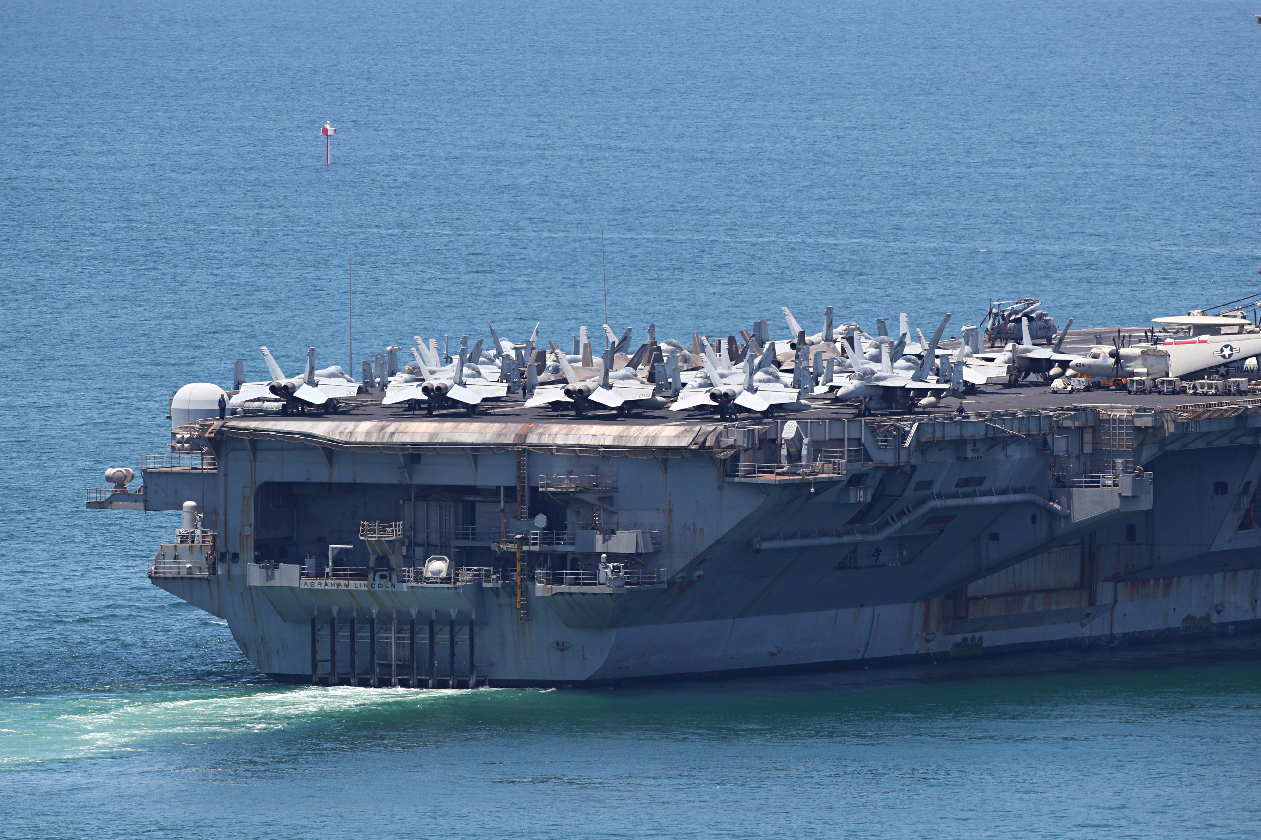 Flugzeugträger USS Abraham Lincoln mit vielen Kampfjets auf Deck fährt auf dem Meer.