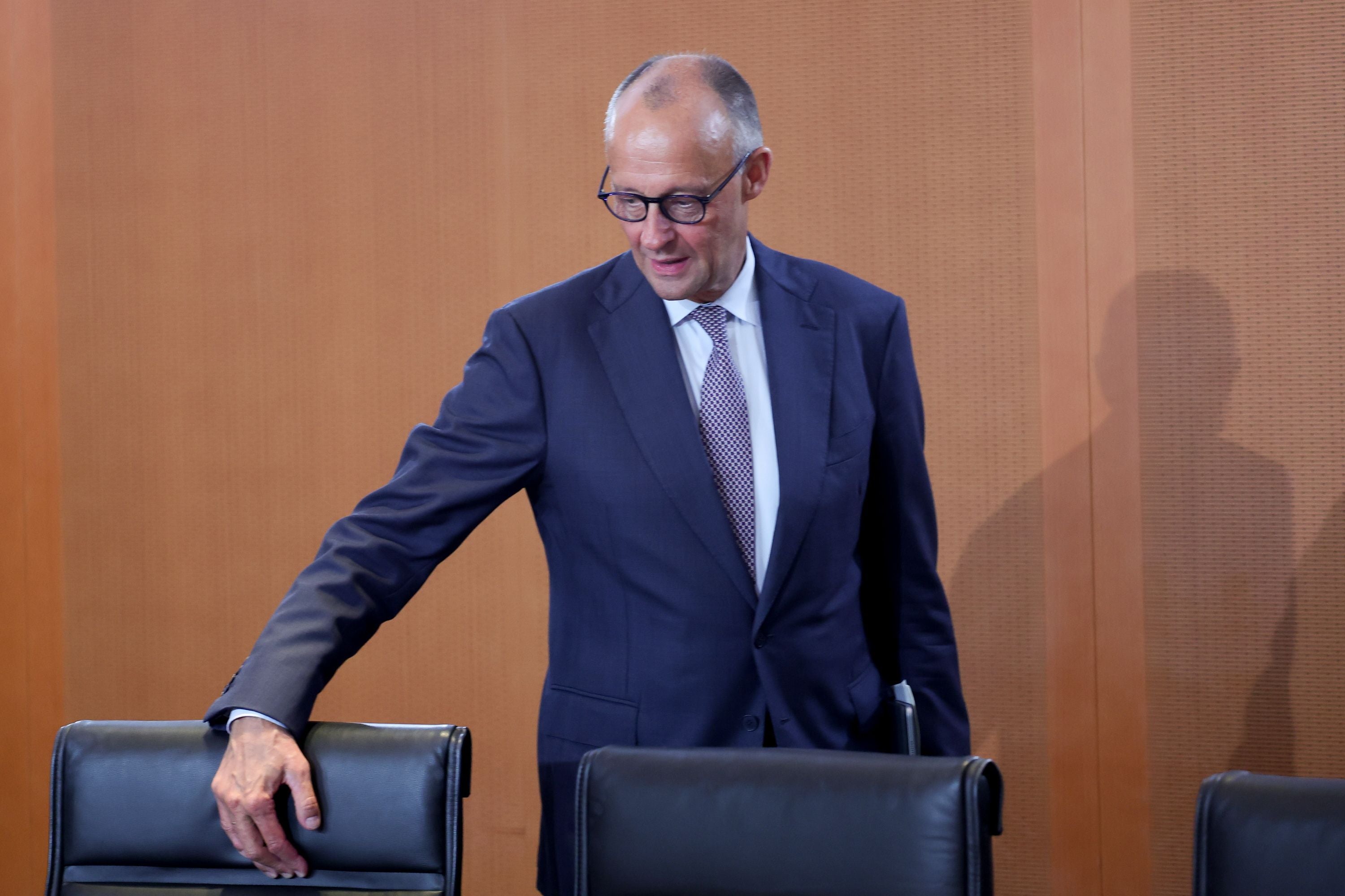 Ein Mann im Anzug steht neben einem Stuhl in einem Konferenzraum.