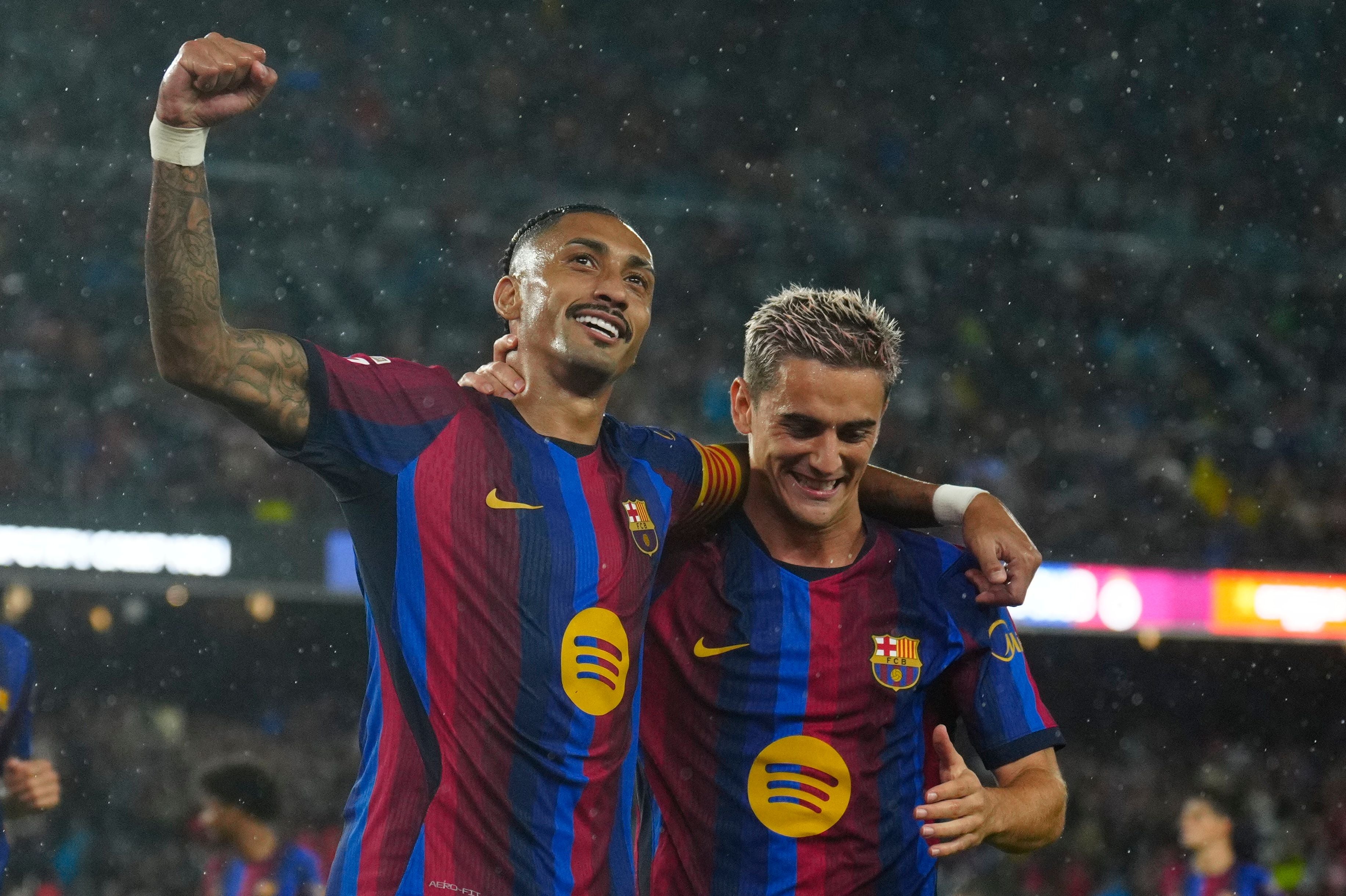 Zwei FC-Barcelona-Spieler jubeln im Regen während eines Fußballspiels im Stadion.