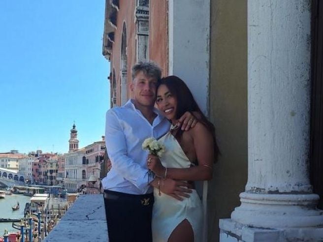 Ein Paar umarmt sich glücklich vor einer Hauswand mit Blick auf den Canal in Venedig.