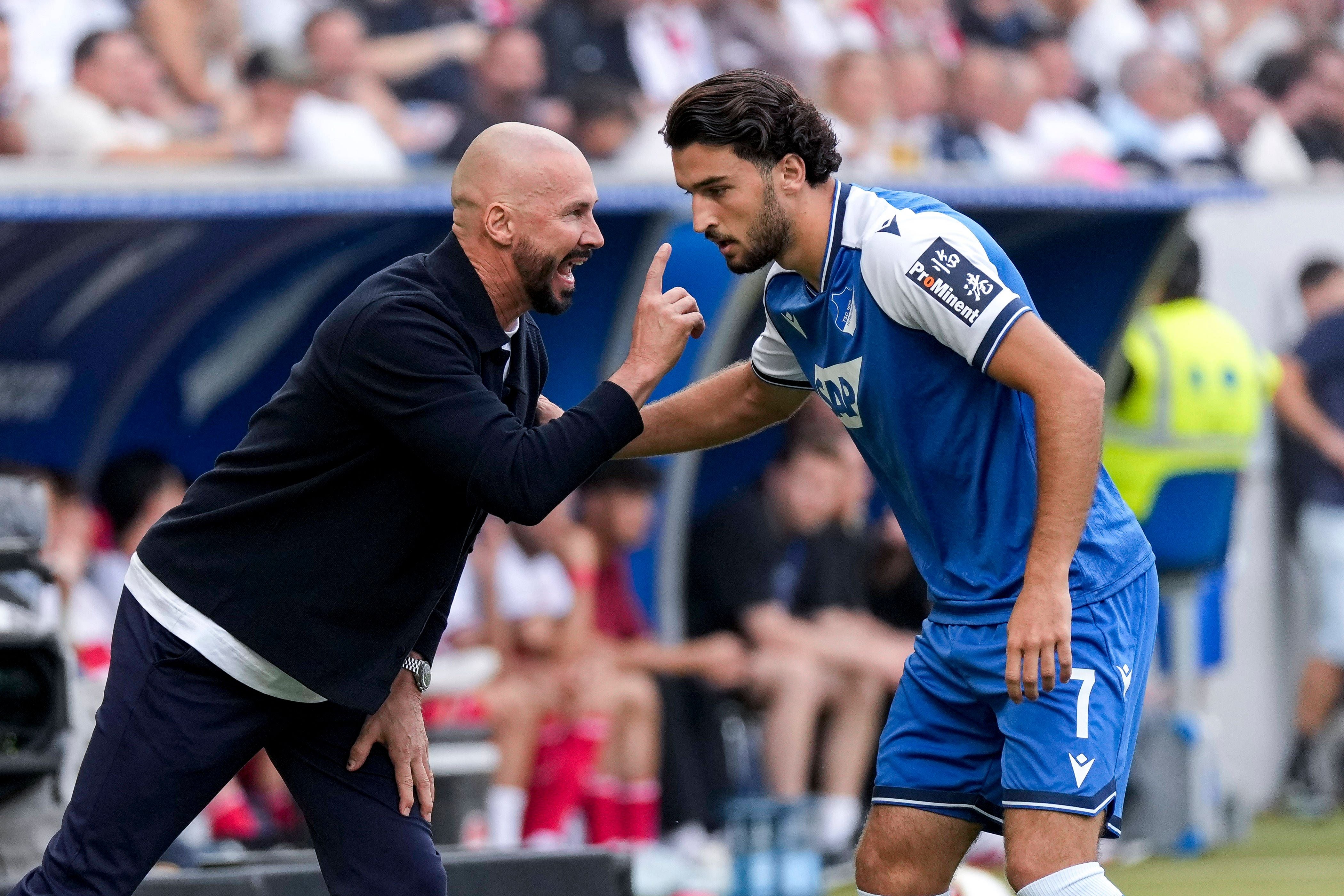Ein Fußballtrainer gibt seinem Spieler am Spielfeldrand gestikulierend Anweisungen.