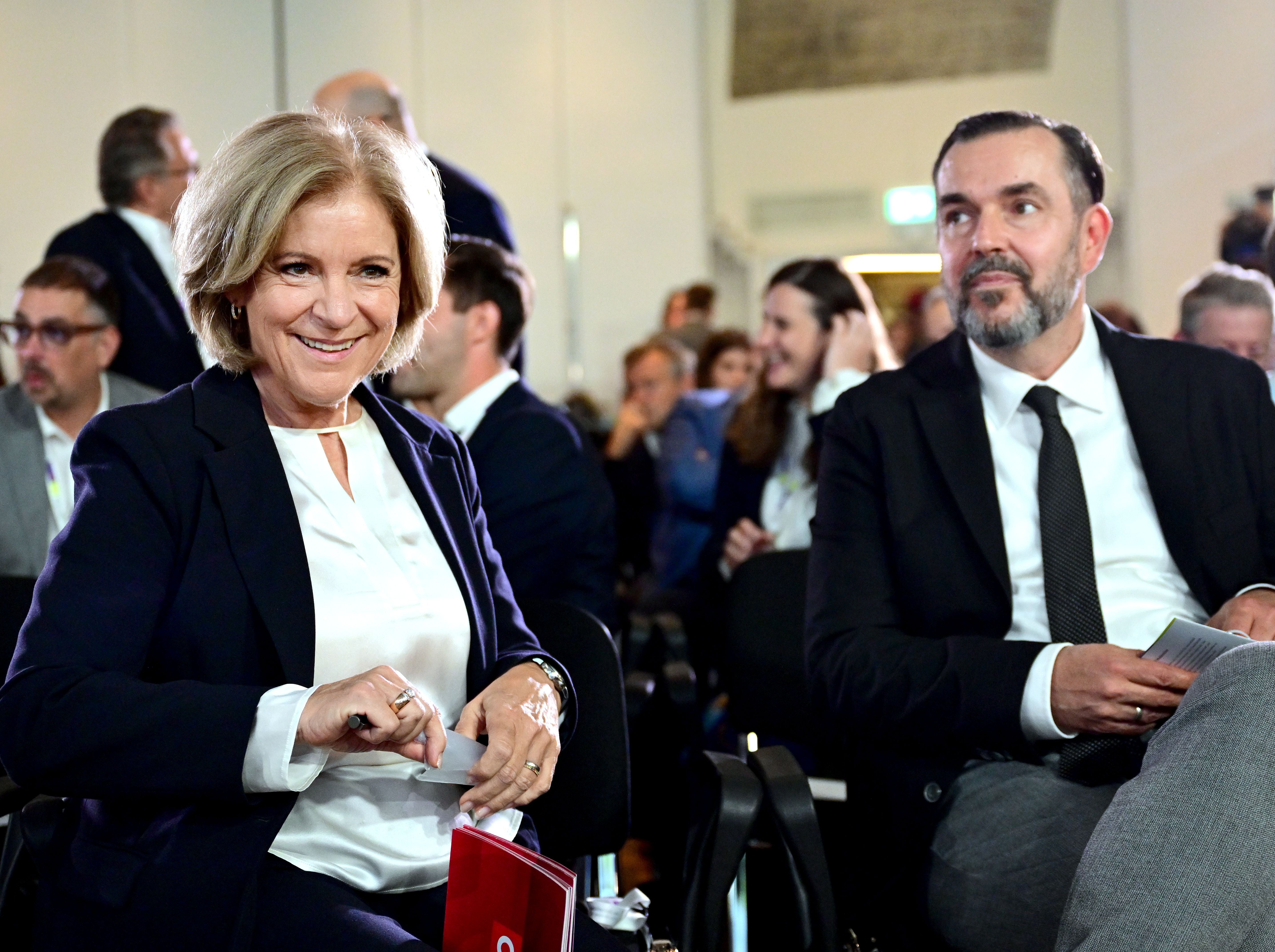 Ingrid Thurnher und Clemens Pig sitzen lächelnd bei einer Podiumsdiskussion in Wien.