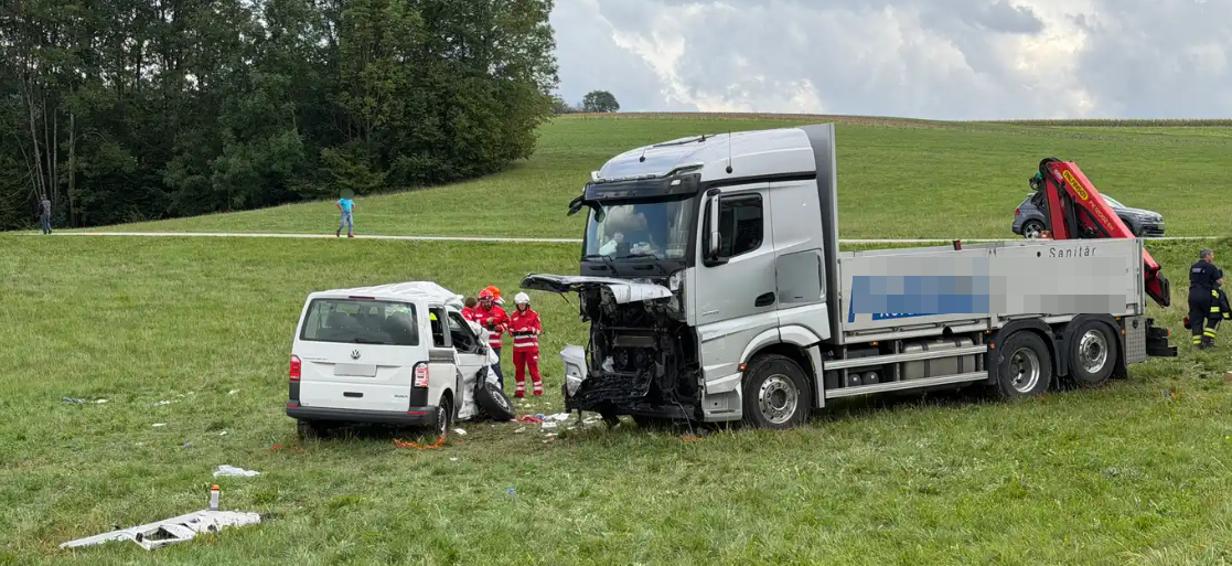 LKW und Kleinbus stehen nach einem Unfall auf einer Wiese, Einsatzkräfte sind vor Ort.