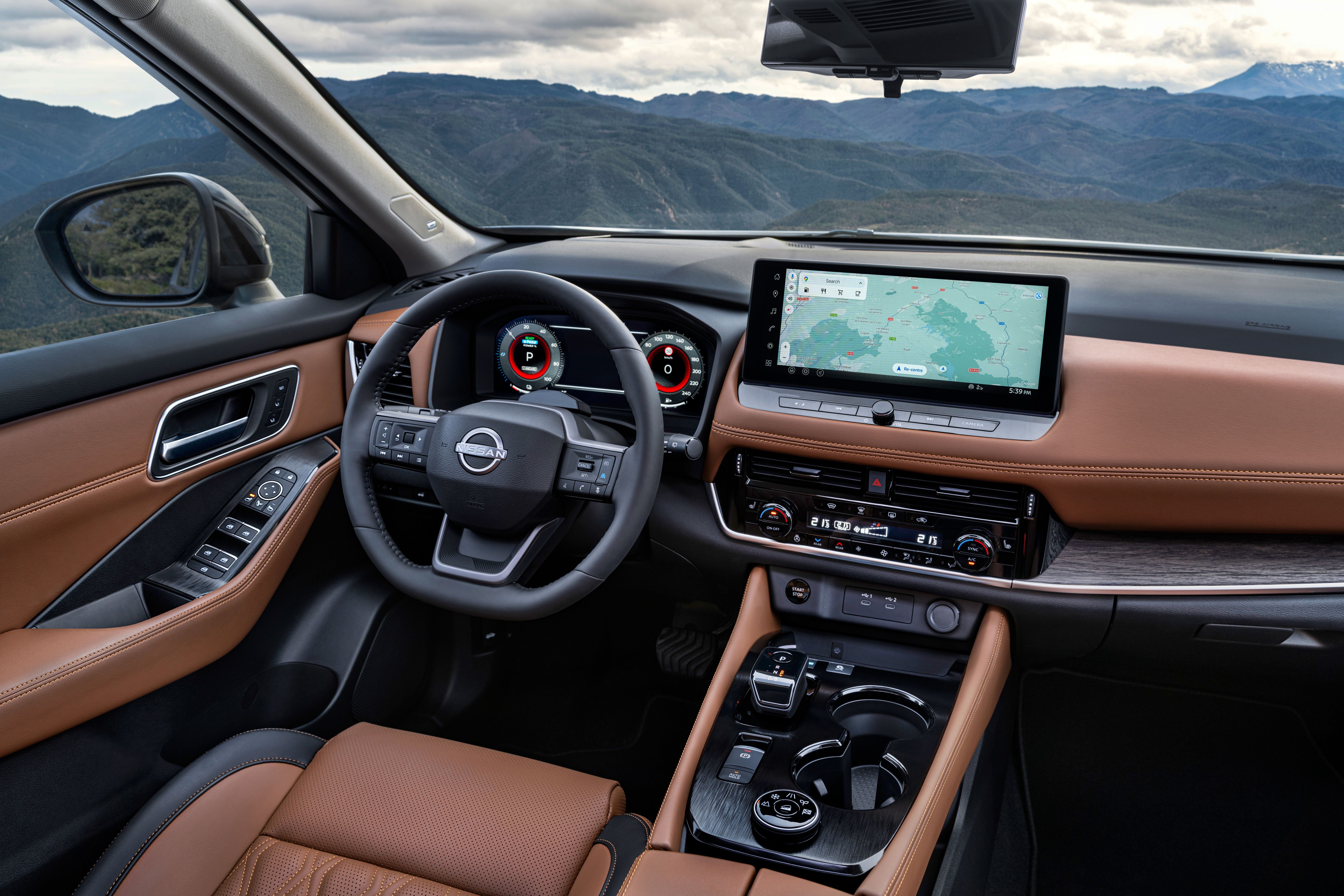 Modernes Nissan-Autointerieur mit braunen Ledersitzen, großem Display und Berglandschaft außen.