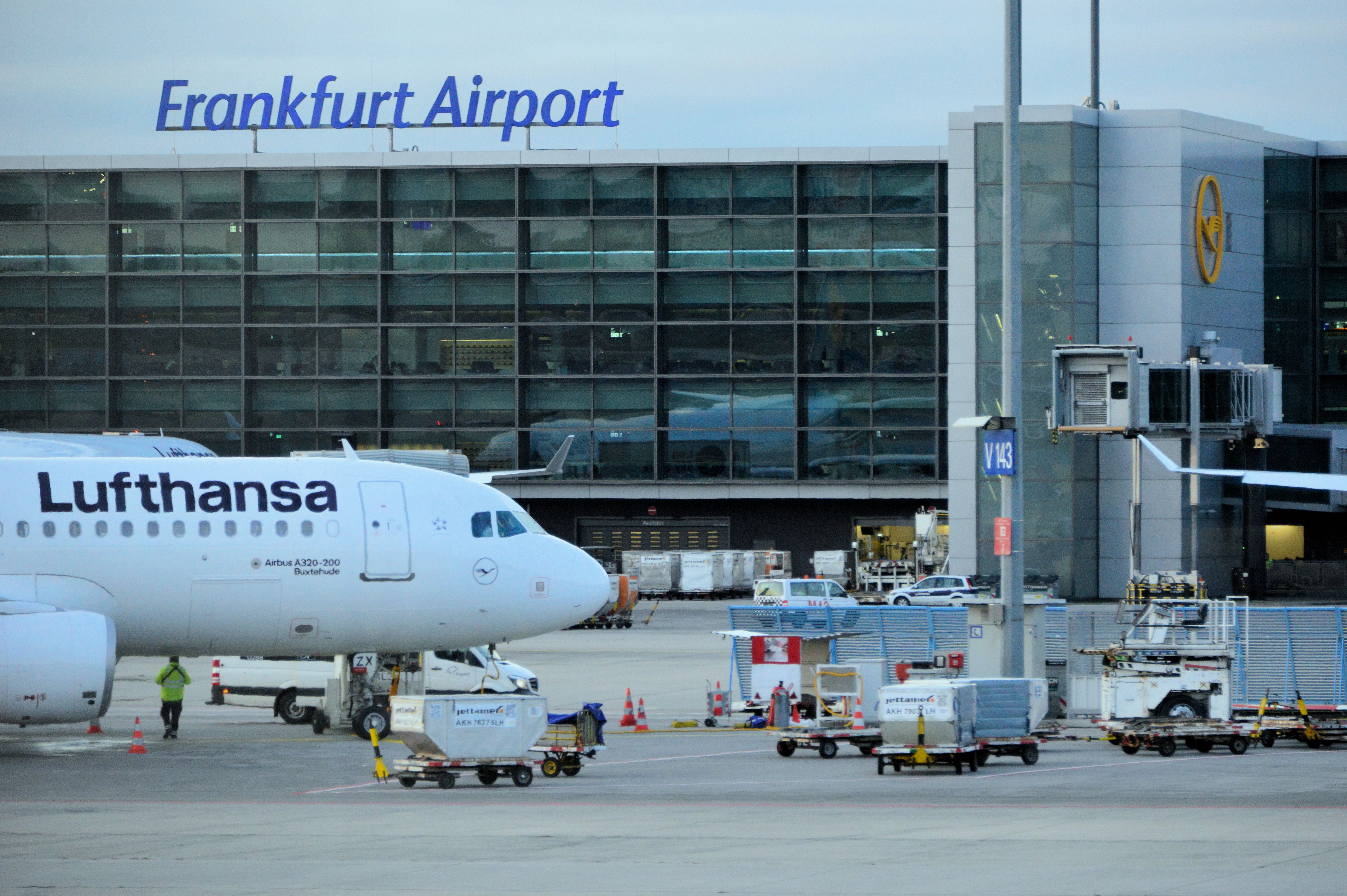 Lufthansa Airbus A320 steht am Terminal des Frankfurter Flughafens mit sichtbarem Flughafenschild.