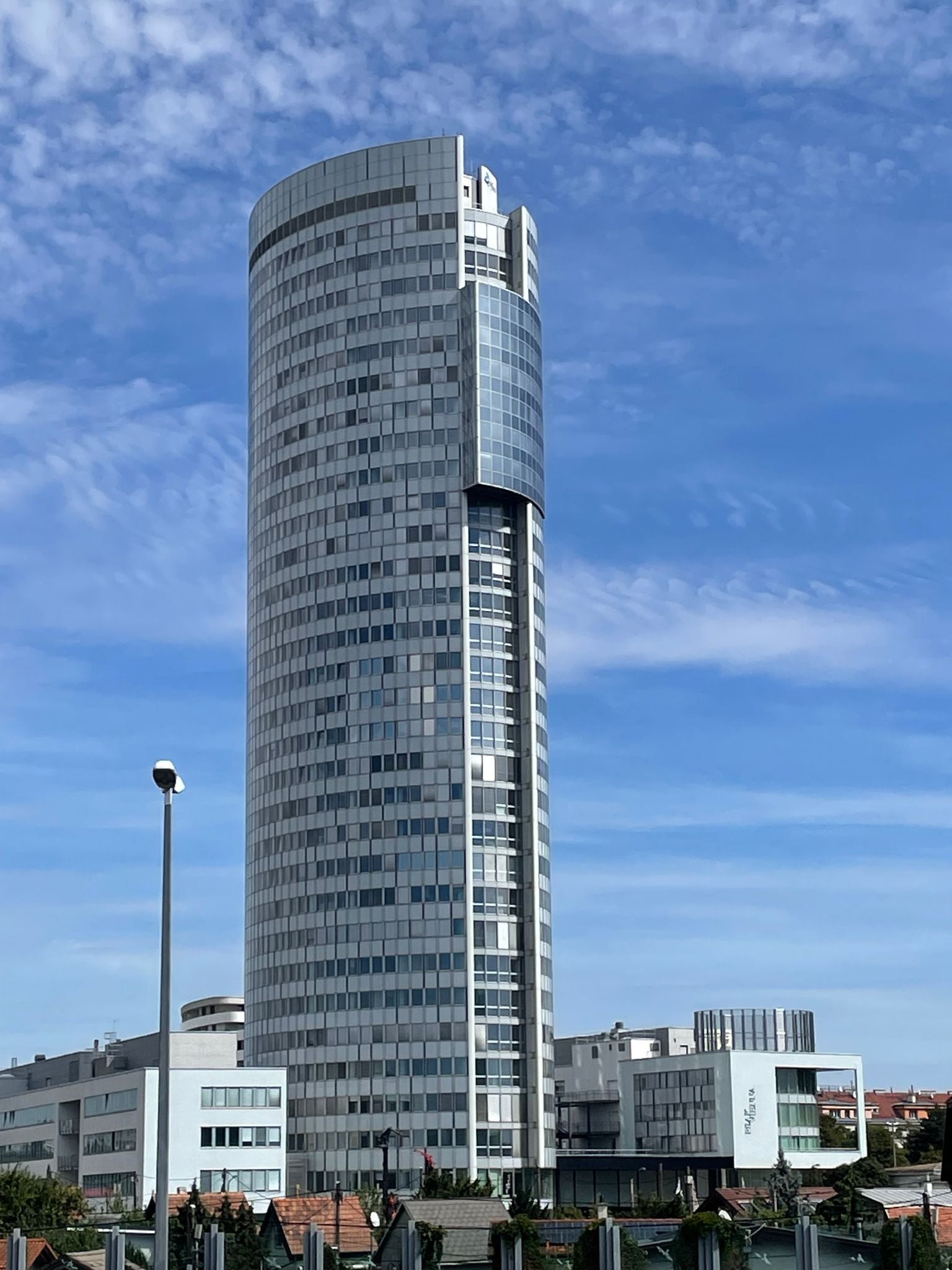 Ein Mann im Anzug blickt freundlich in die Kamera, unscharfer Hintergrund mit Leuchtschrift.