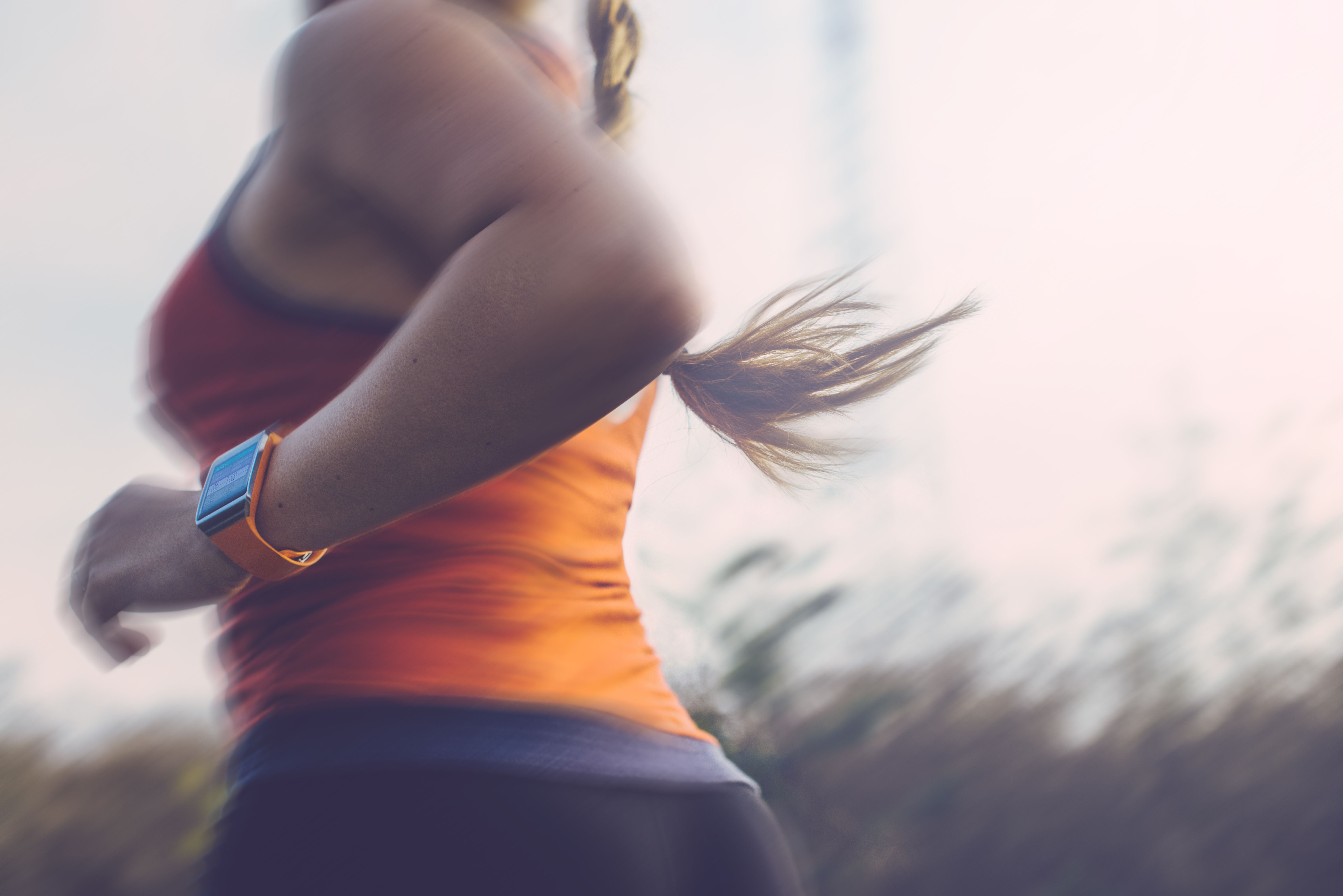 Frau joggt draußen und trägt eine Smartwatch am Handgelenk.