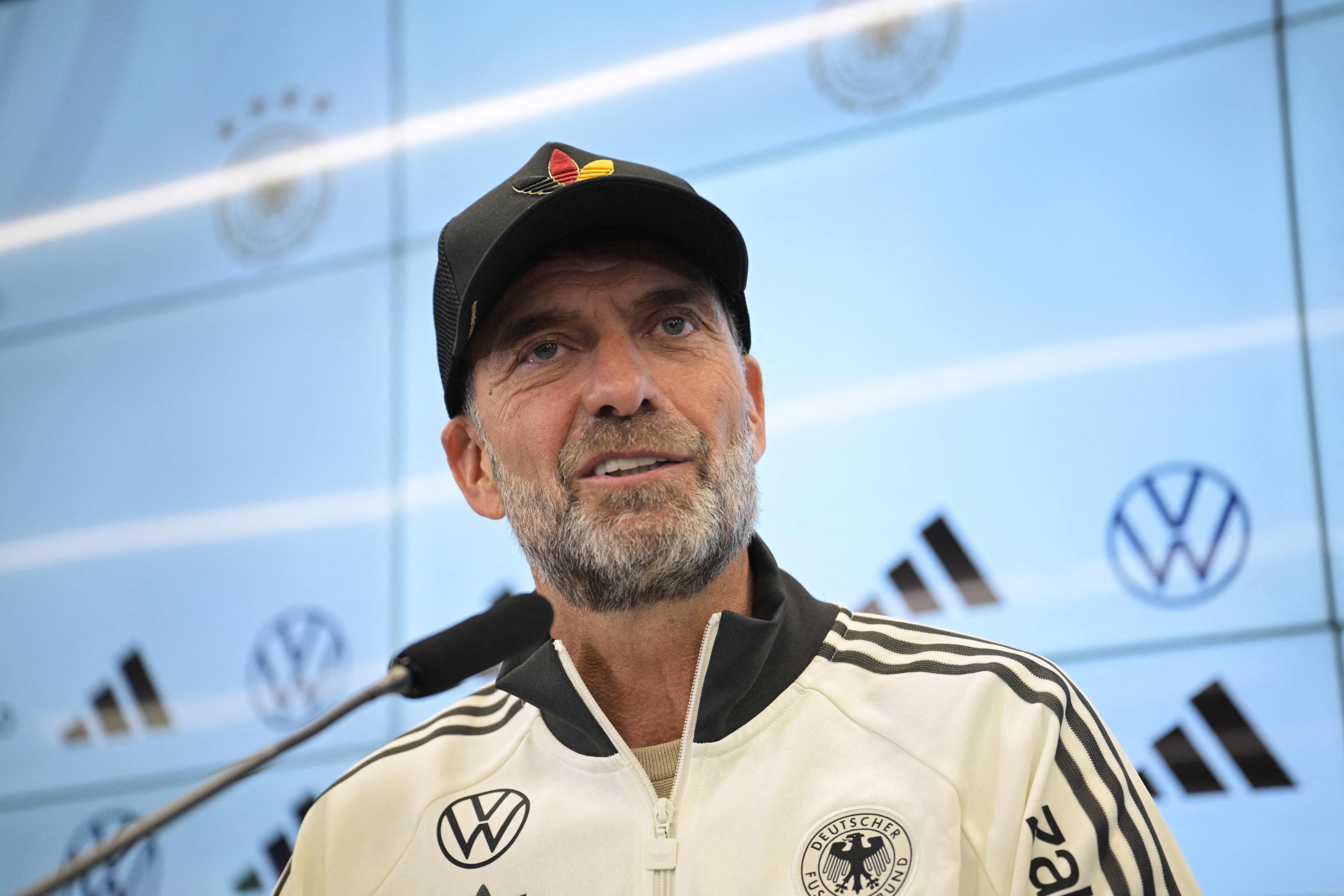 Ein Mann im DFB-Trainingsanzug spricht bei einer Pressekonferenz mit Mikrofon.