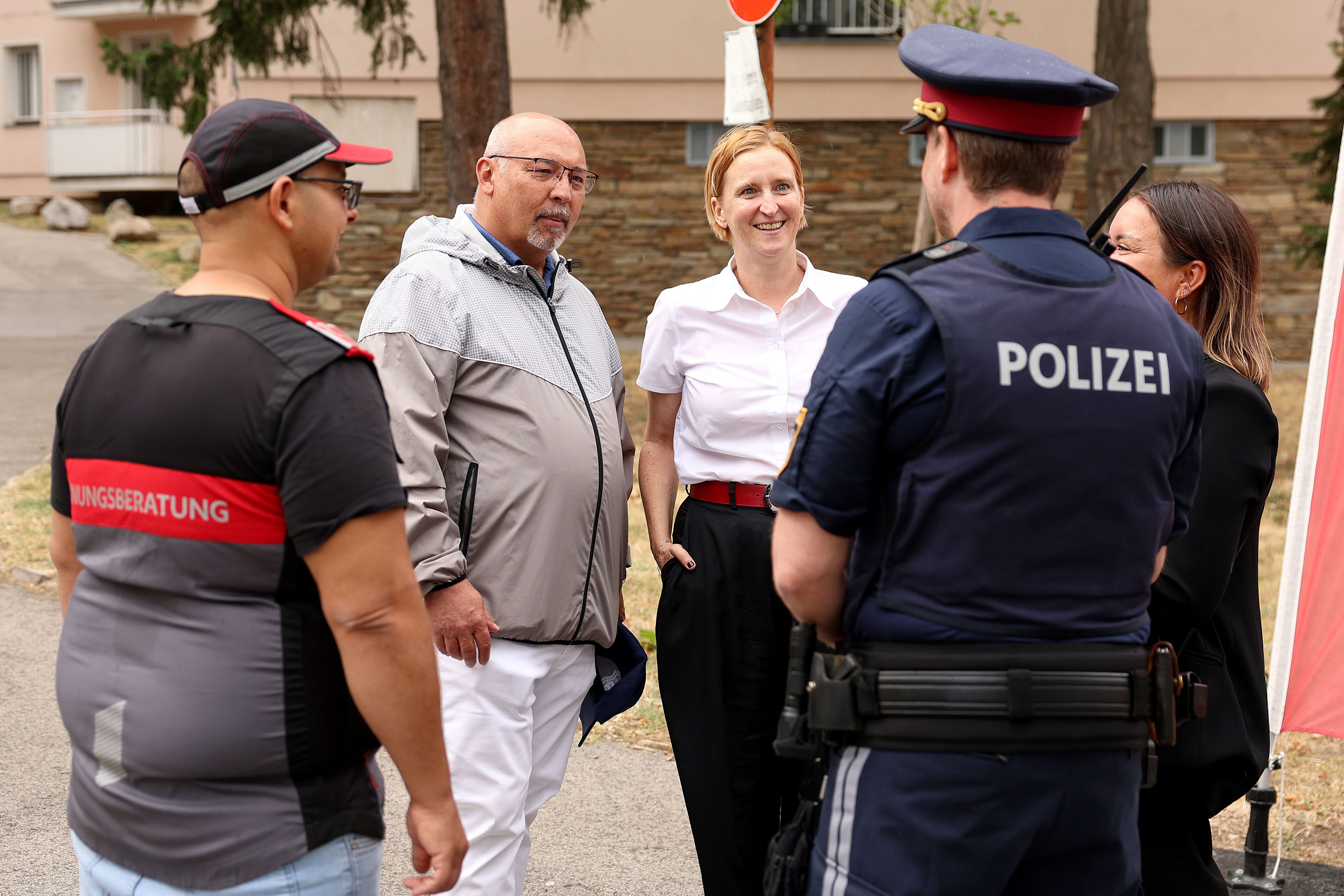 Mehrere Personen, darunter Polizei und Organisator:innen, unterhalten sich im Freien am Ernest-Bevin-Hof.