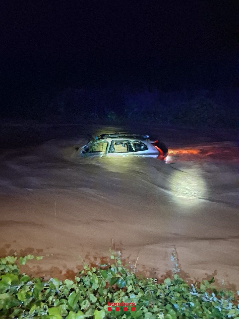 Auto ist nachts fast vollständig von Hochwasser umgeben, nur das Dach ragt heraus.