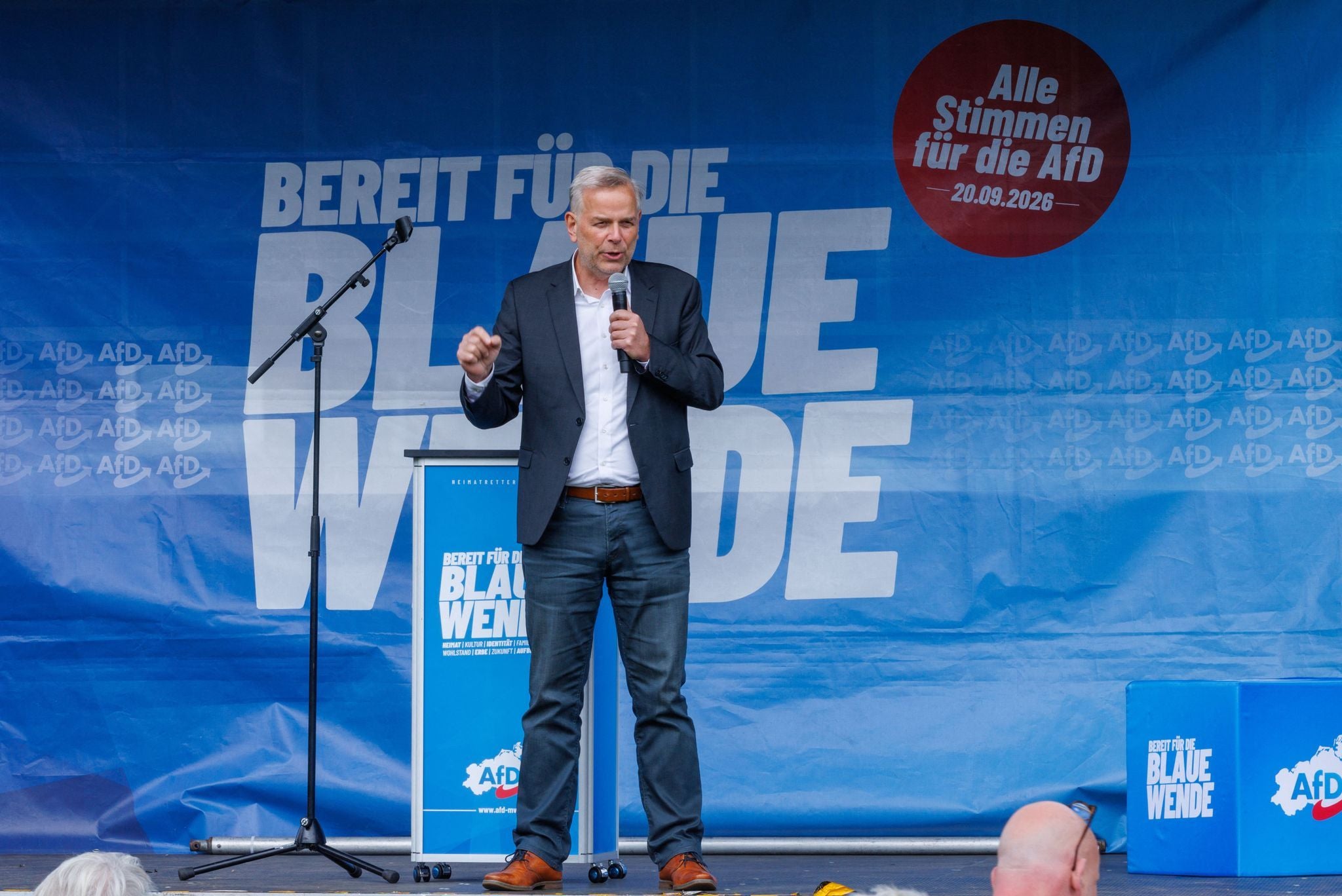Ein Mann spricht mit Mikrofon auf einer AfD-Bühne bei einer Wahlkampfveranstaltung.