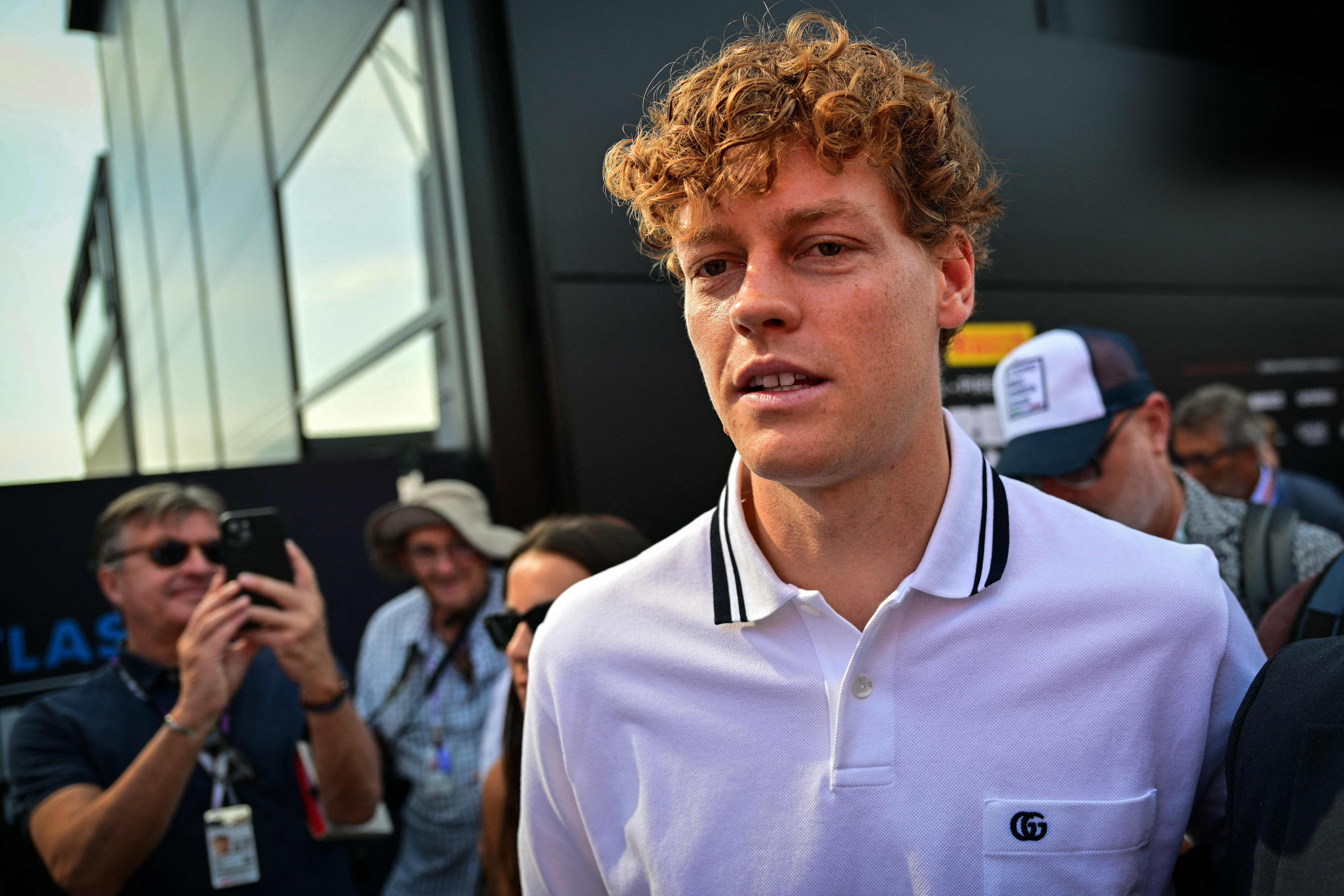 Jannik Sinner in weißem Polohemd auf dem Weg zum Formel-1-Rennen in Monza, Menschen im Hintergrund.