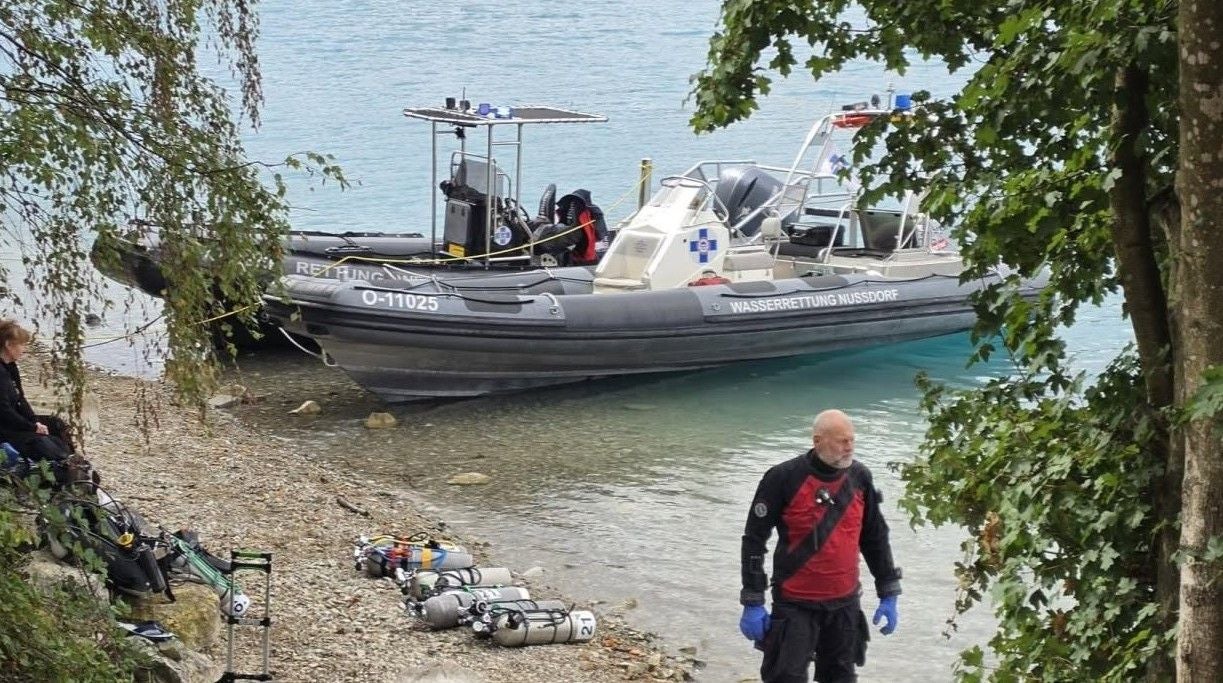 Rettungsboot der Wasserrettung am Ufer des Attersees, Taucher in Einsatzkleidung am Ufer.