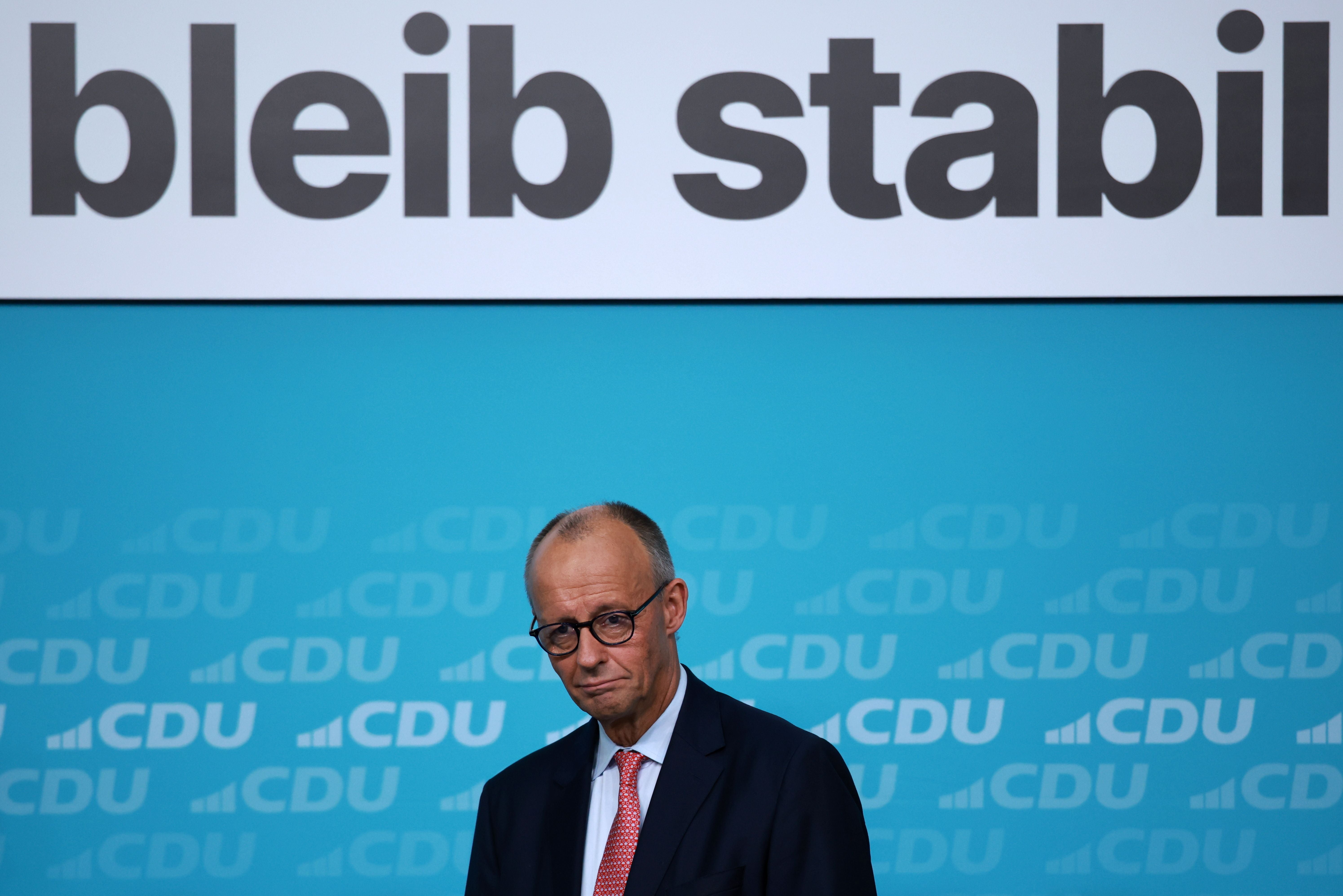 Ein Mann steht vor einer blauen CDU-Wand, darüber der Schriftzug „bleib stabil“.