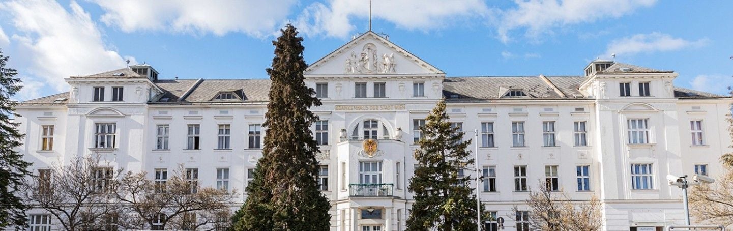 Die Fassade der Klinik Hietzing in Wien bei blauem Himmel und Sonnenschein.
