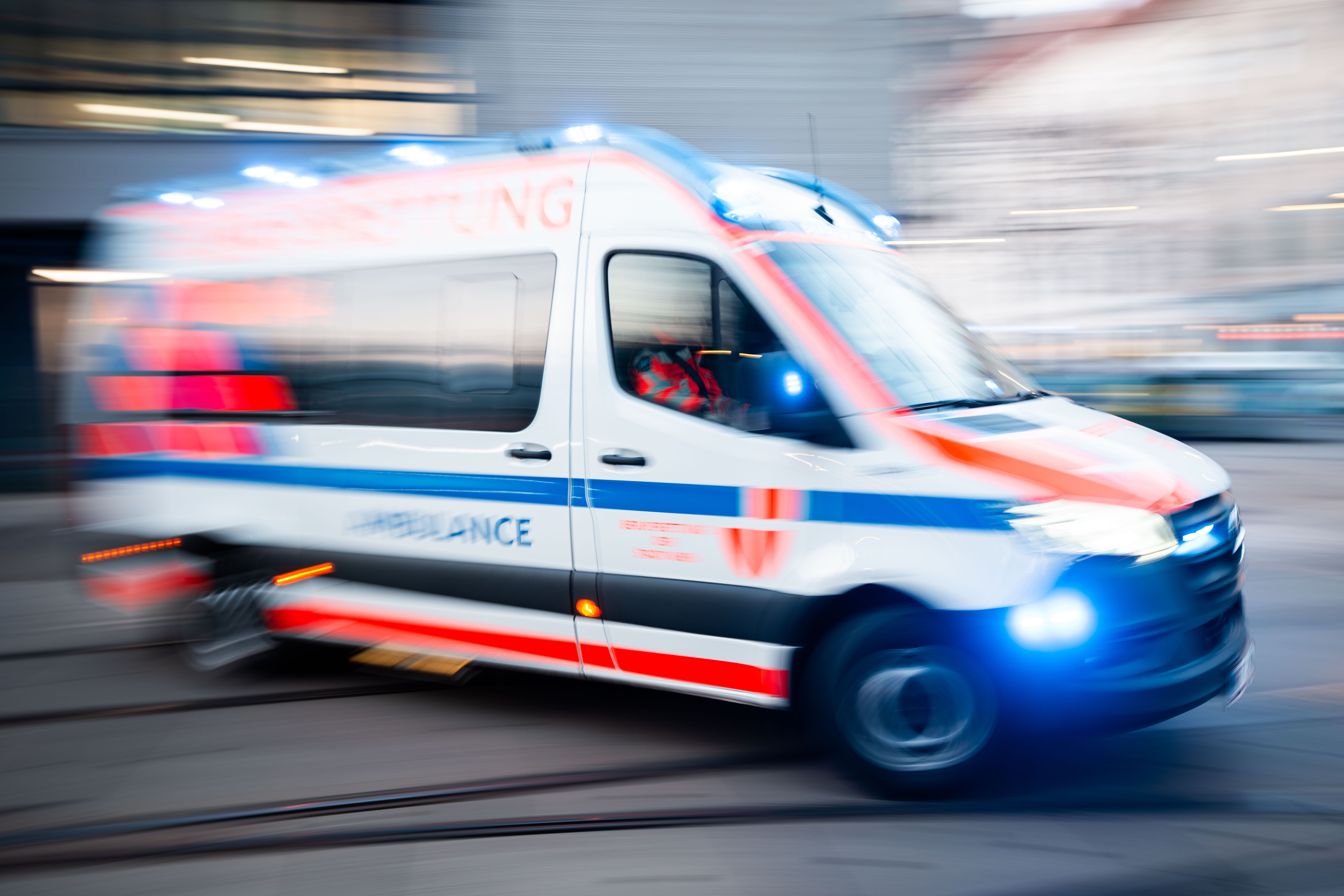 Ein Rettungswagen mit Blaulicht fährt schnell durch eine Stadt.