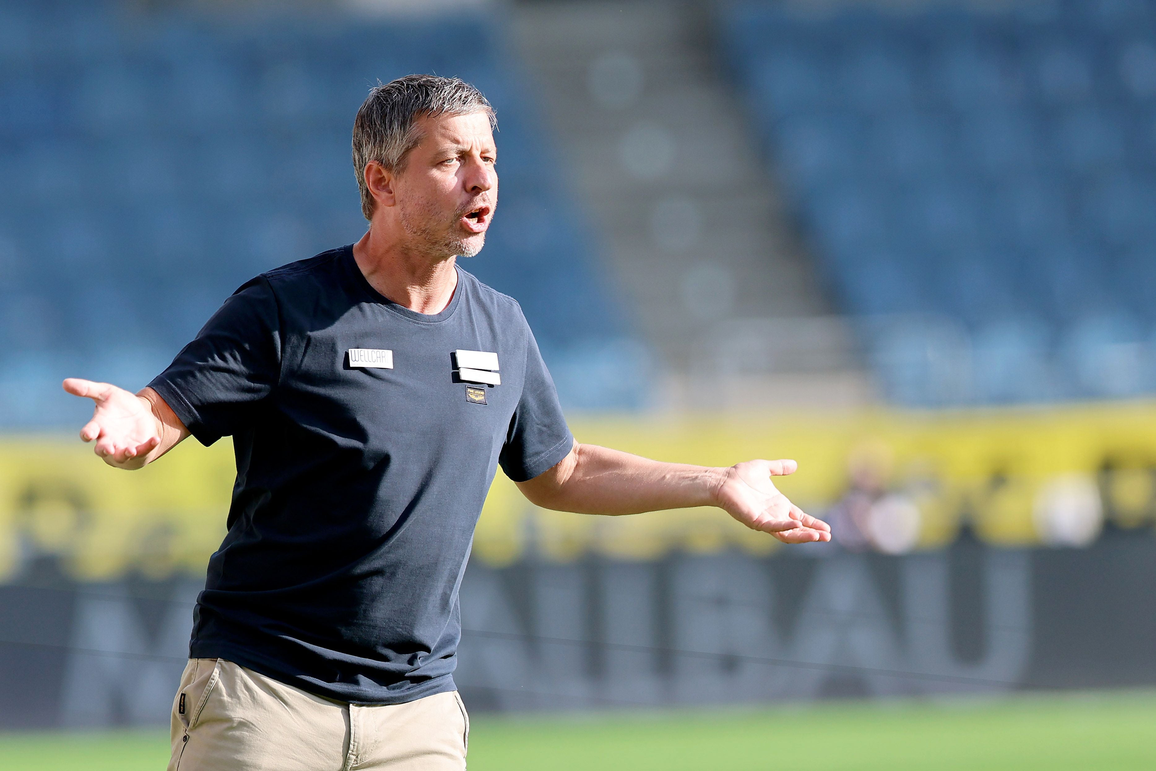 Gerald Scheiblehner steht am Spielfeldrand und gestikuliert mit offenen Händen.