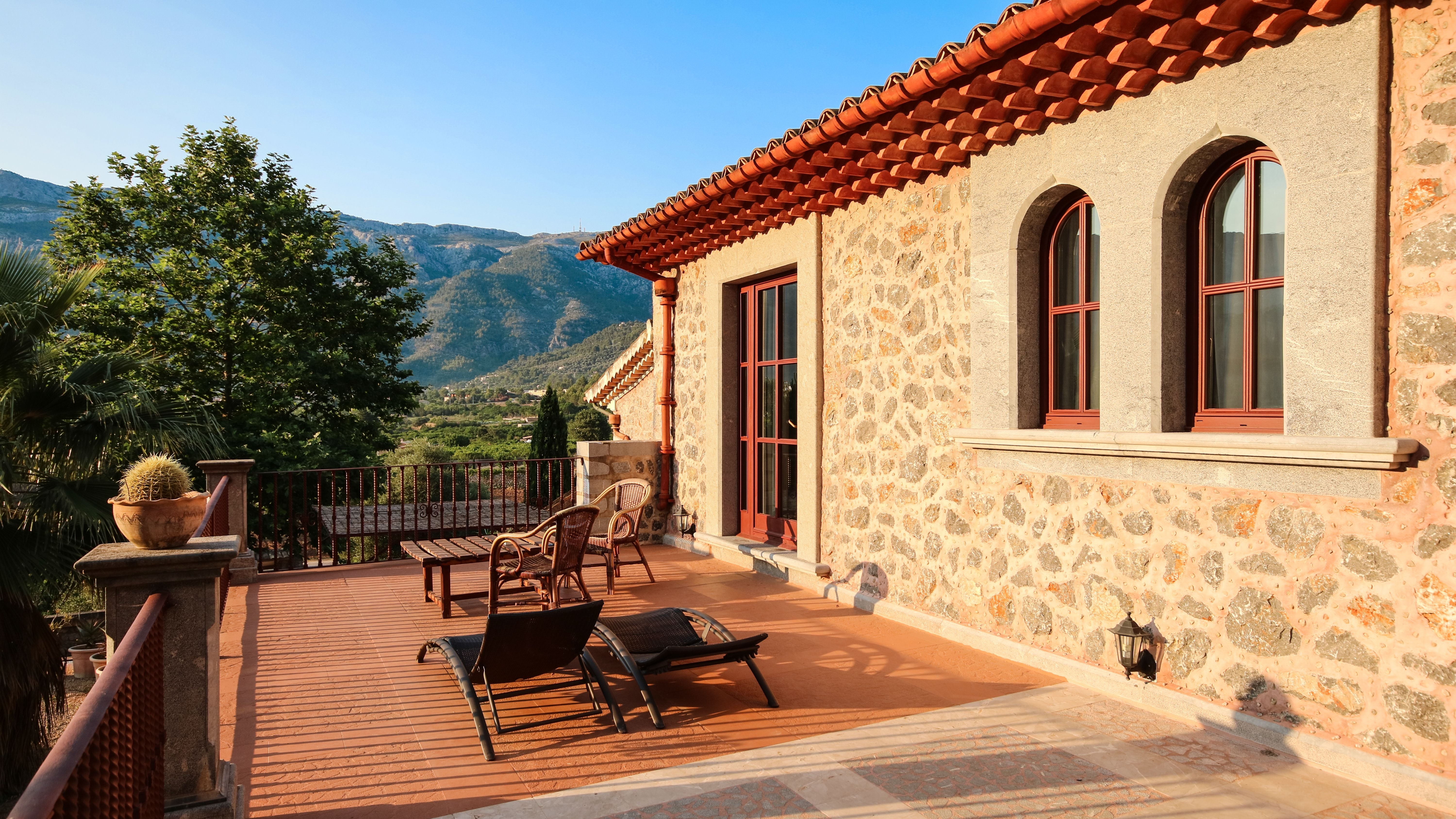 Steinterrasse einer Finca mit Liegestühlen und Bergblick in Port de Soller, Mallorca.