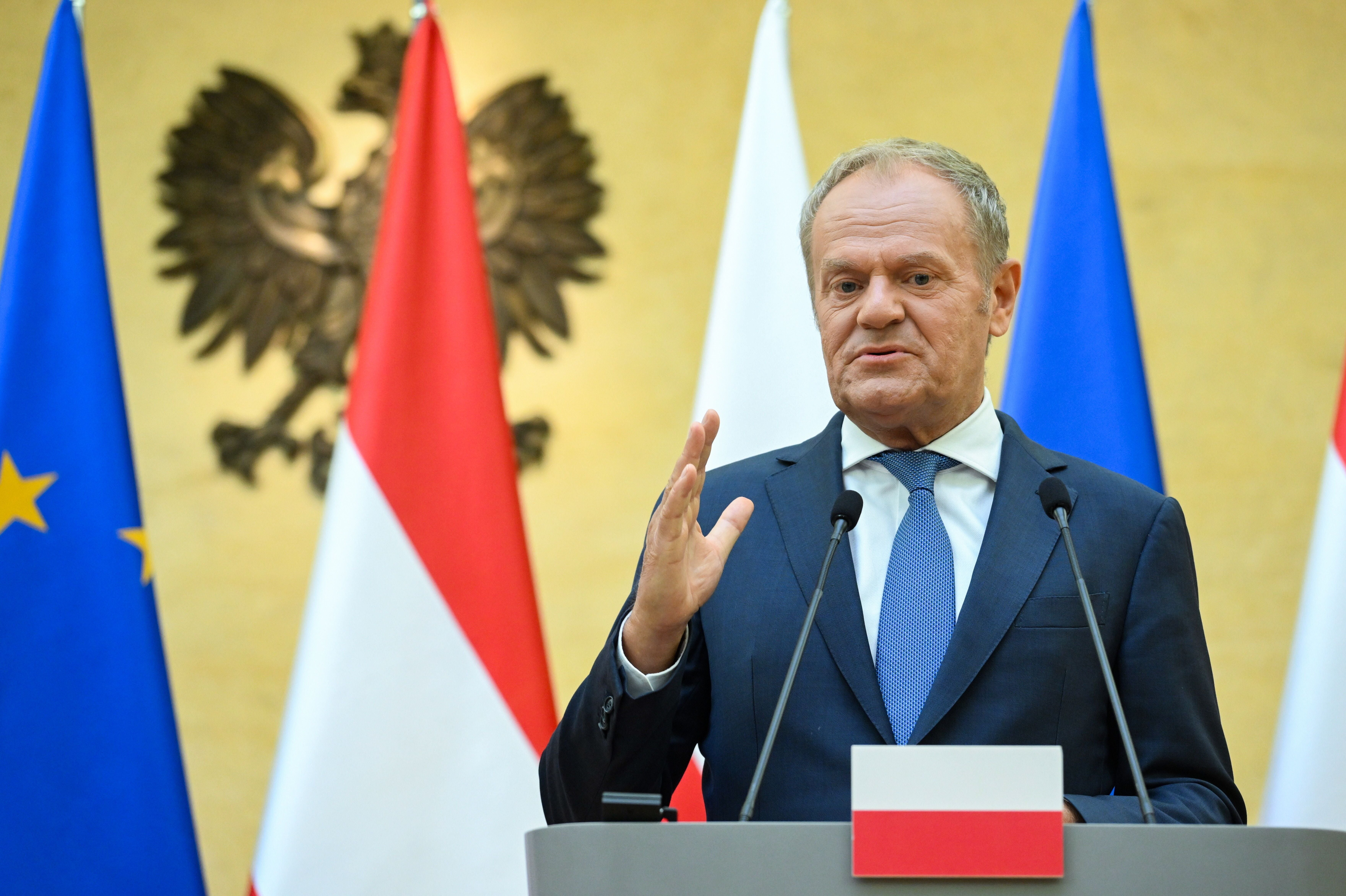 Ein Mann spricht bei einer Pressekonferenz vor Mikrofonen und mehreren Landesflaggen.