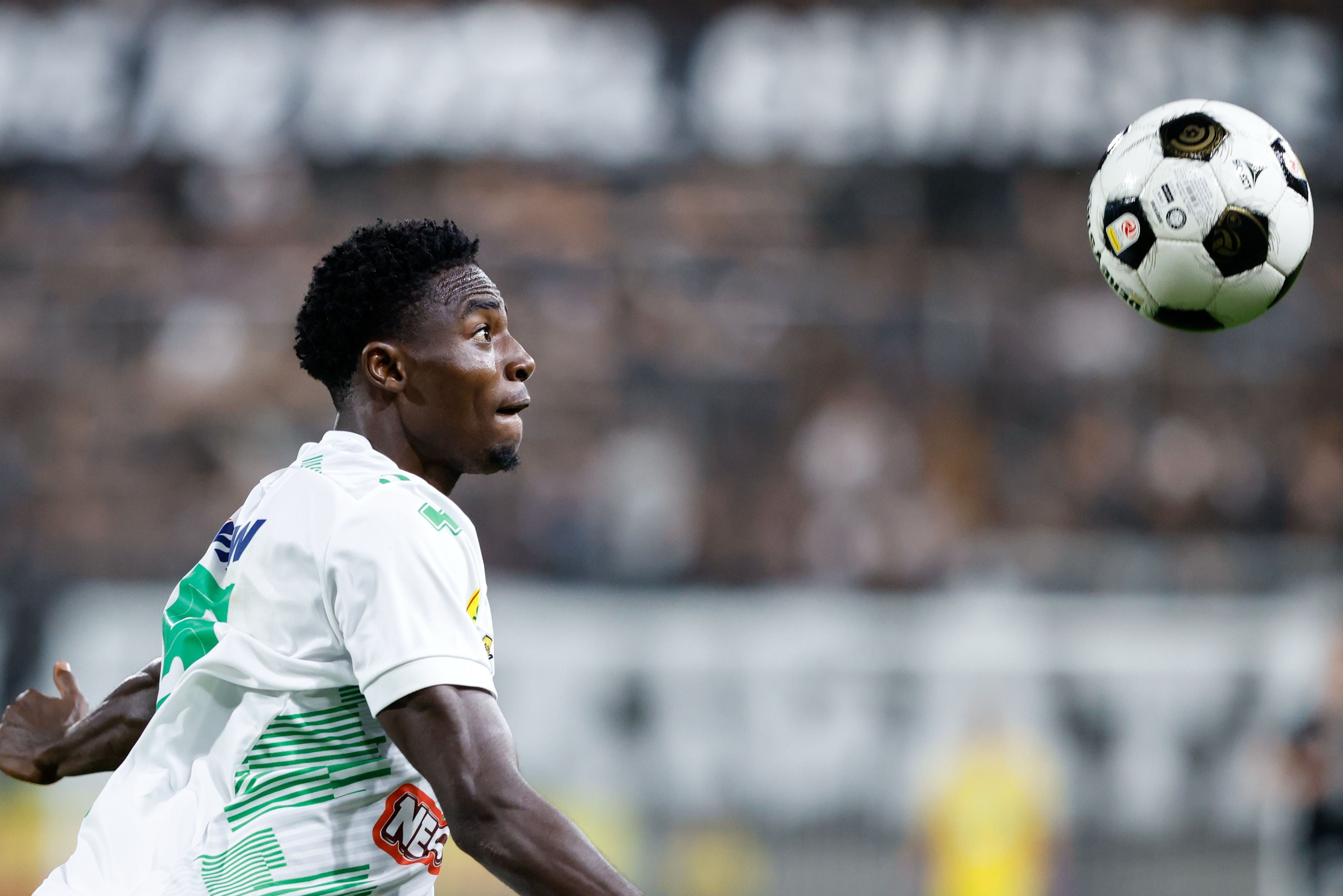 Emmanuel Chukwu im grün-weißen Trikot blickt fokussiert auf einen nahe vor ihm fliegenden Fußball.