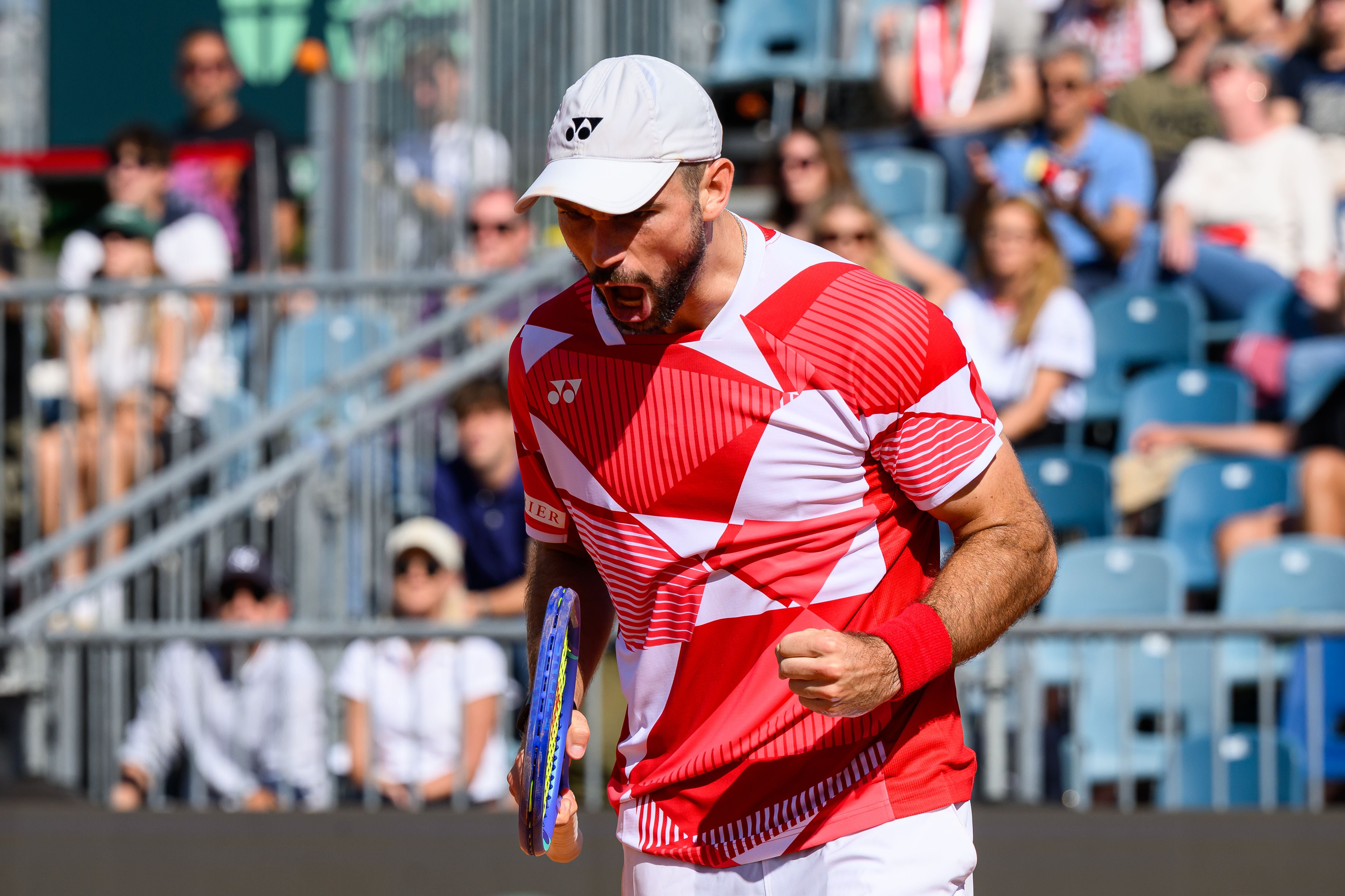 Ein Tennis­spieler im rot-weißen Trikot jubelt mit geballter Faust auf dem Platz.