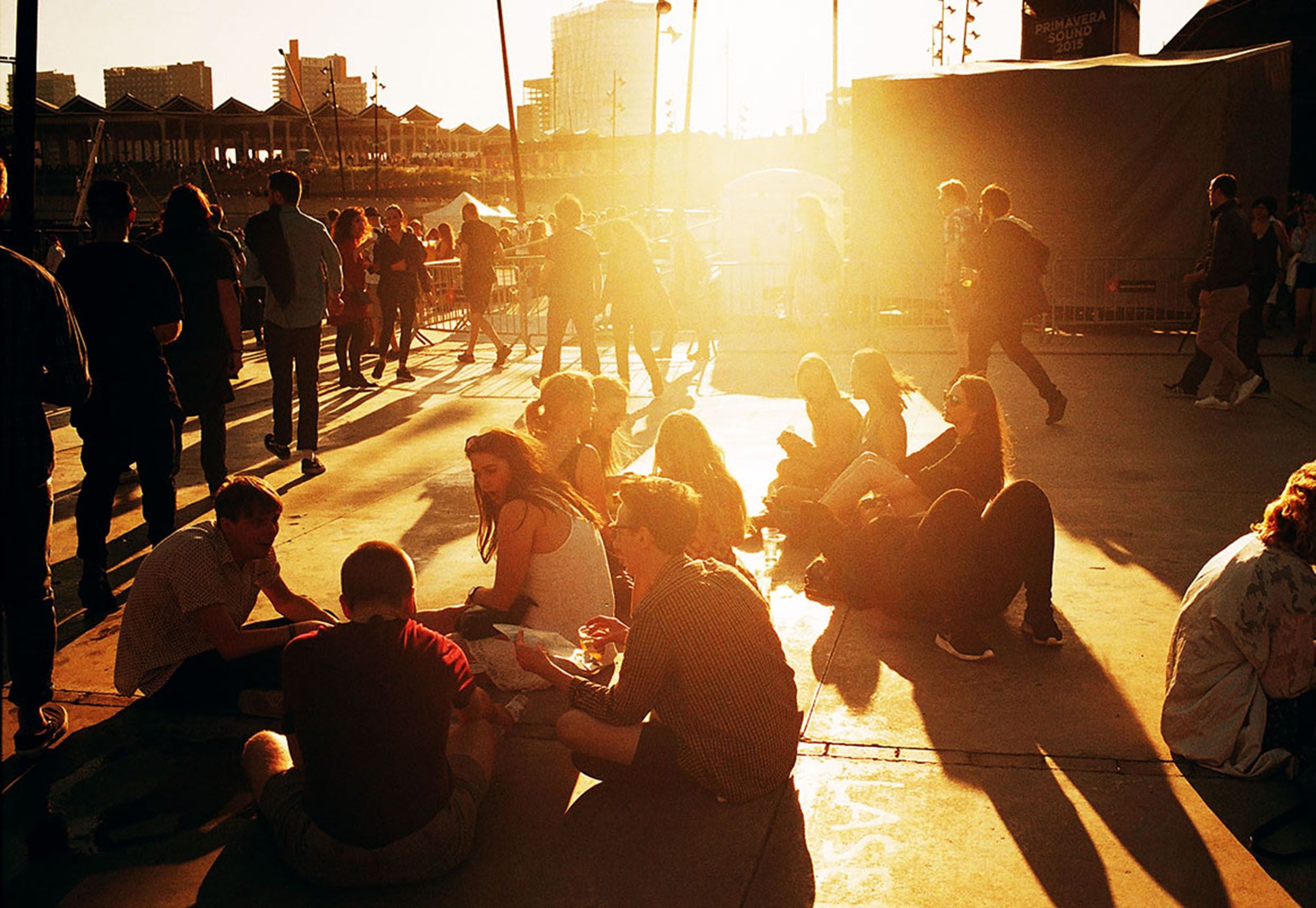 Menschen sitzen und entspannen in der Sonne auf dem Gelände des Primavera Sound Festivals.