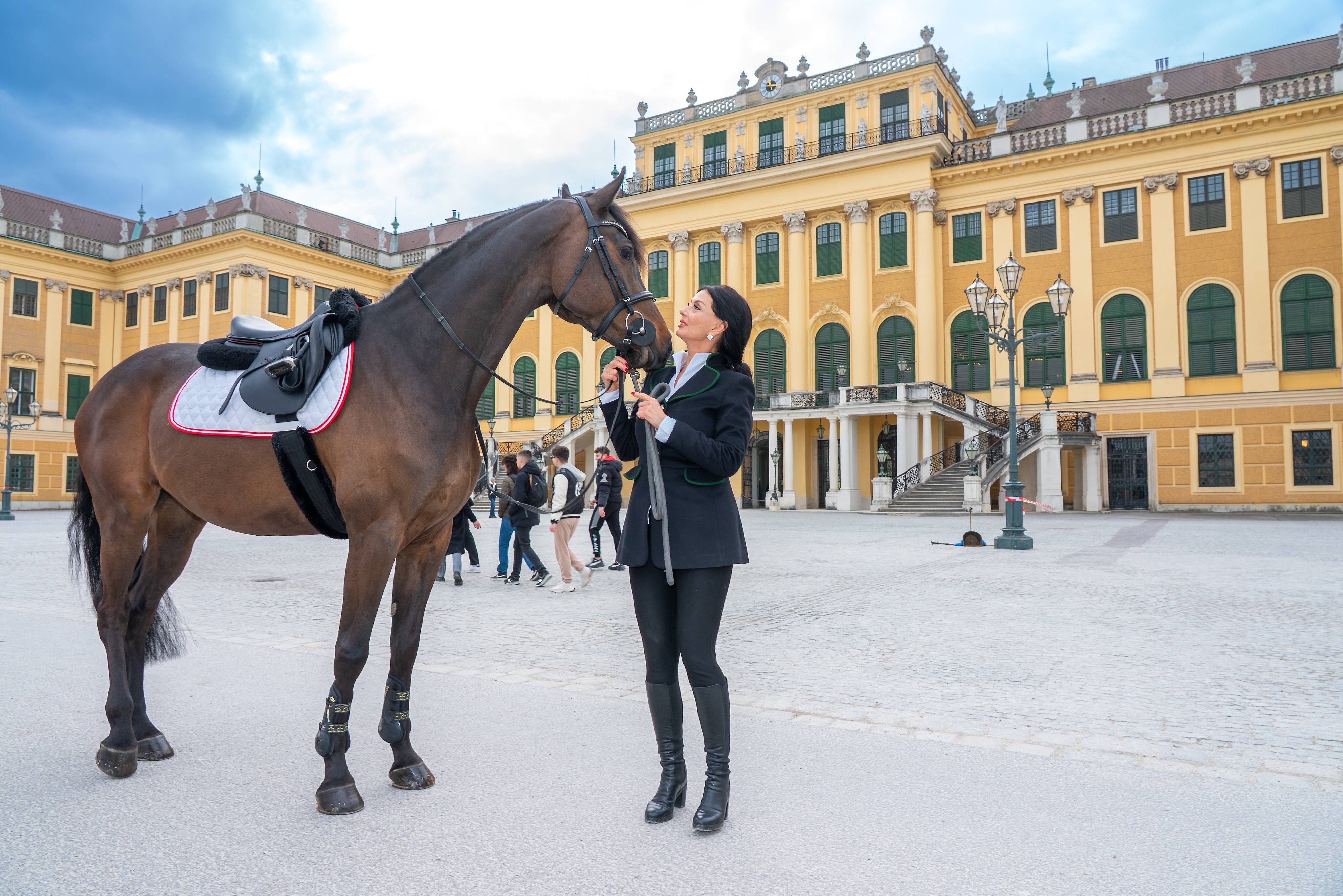 Frau mit Pferd im Ehrenhof von Schloss Schönbrunn in Wien, im Hintergrund das Schloss.