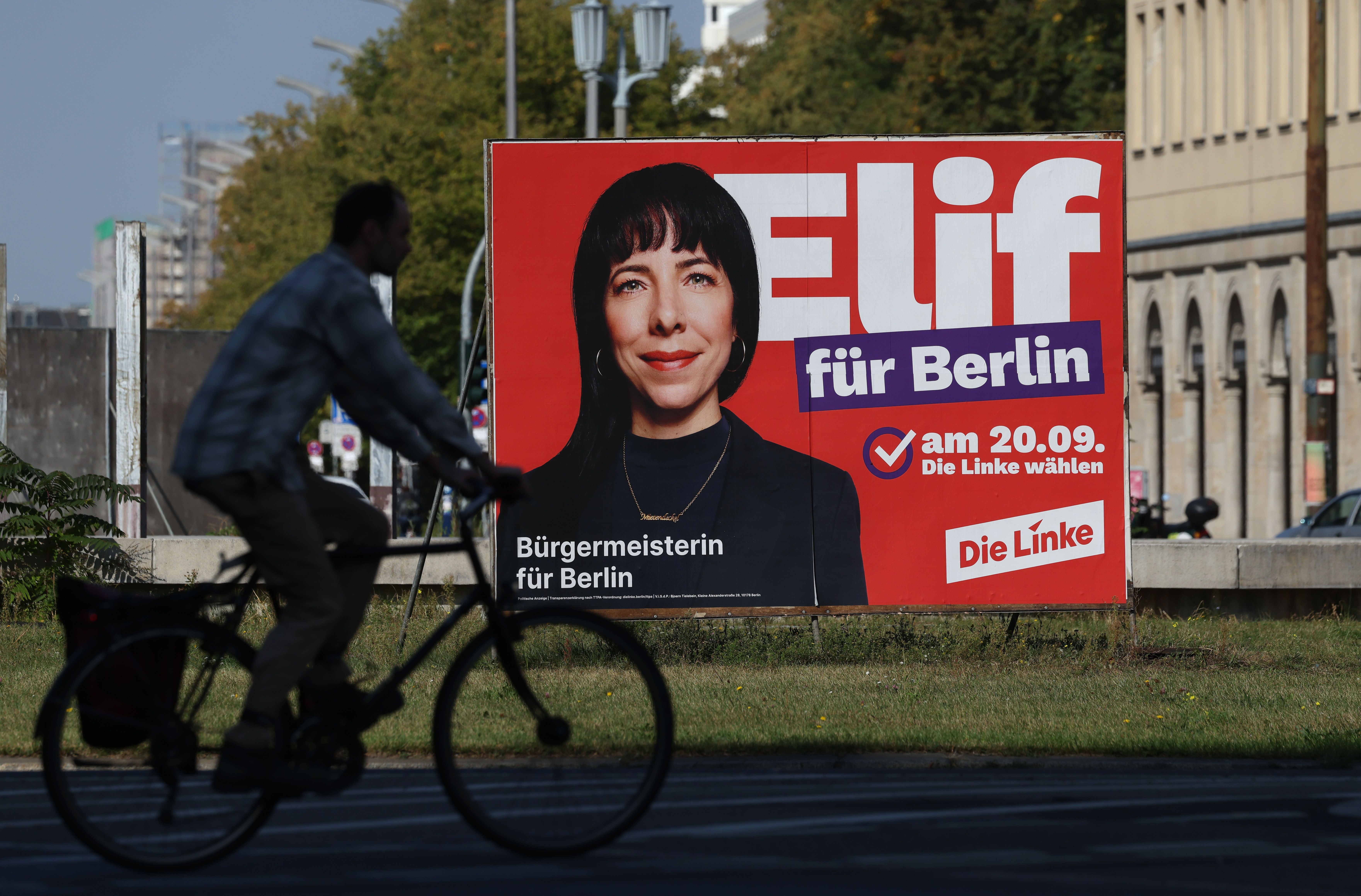 Ein Wahlplakat von Die Linke mit Elif Eralp und dem Slogan „für Berlin“, davor fährt ein Radfahrer vorbei.