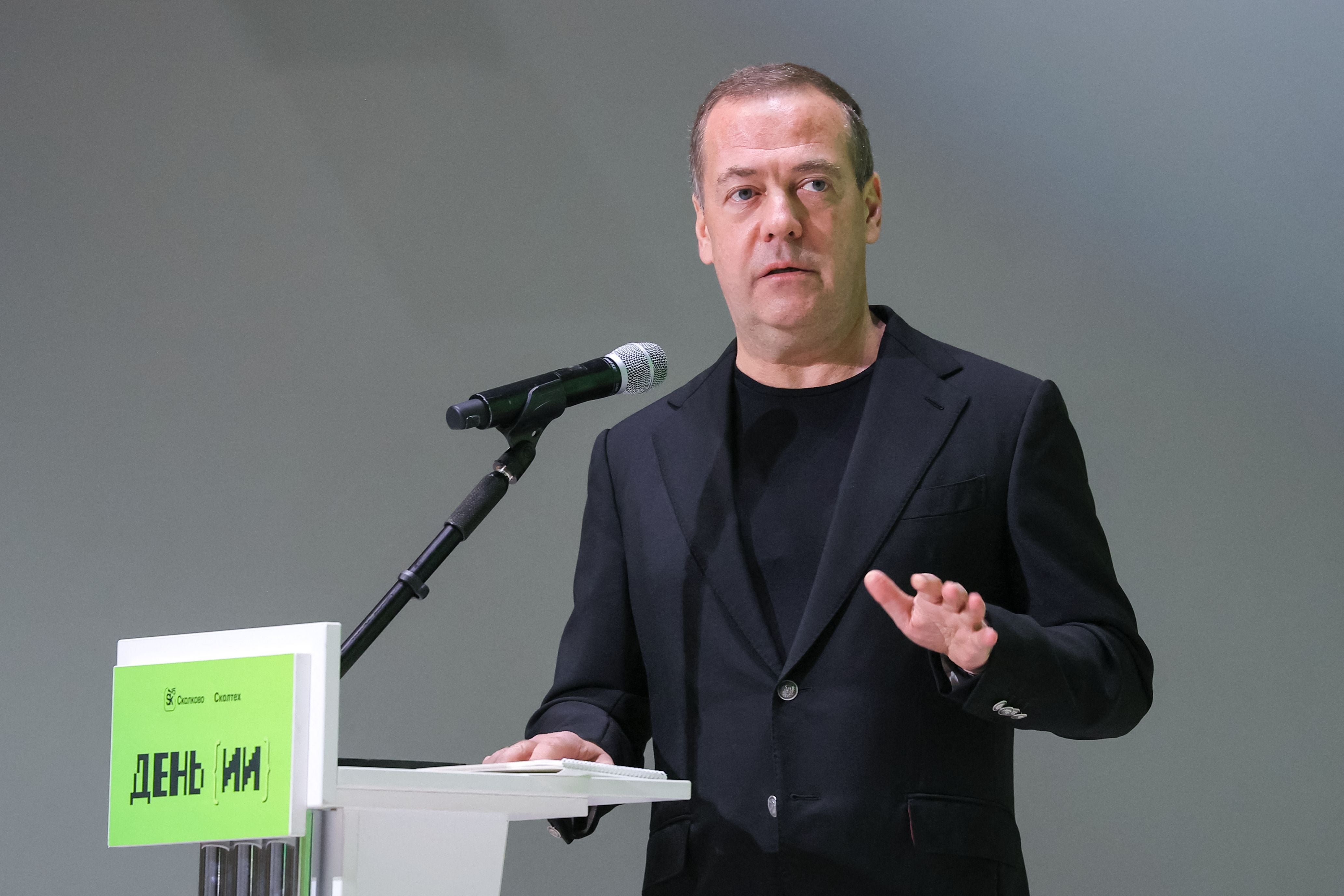 Ein Mann im schwarzen Anzug spricht bei einer Veranstaltung am Mikrofon.