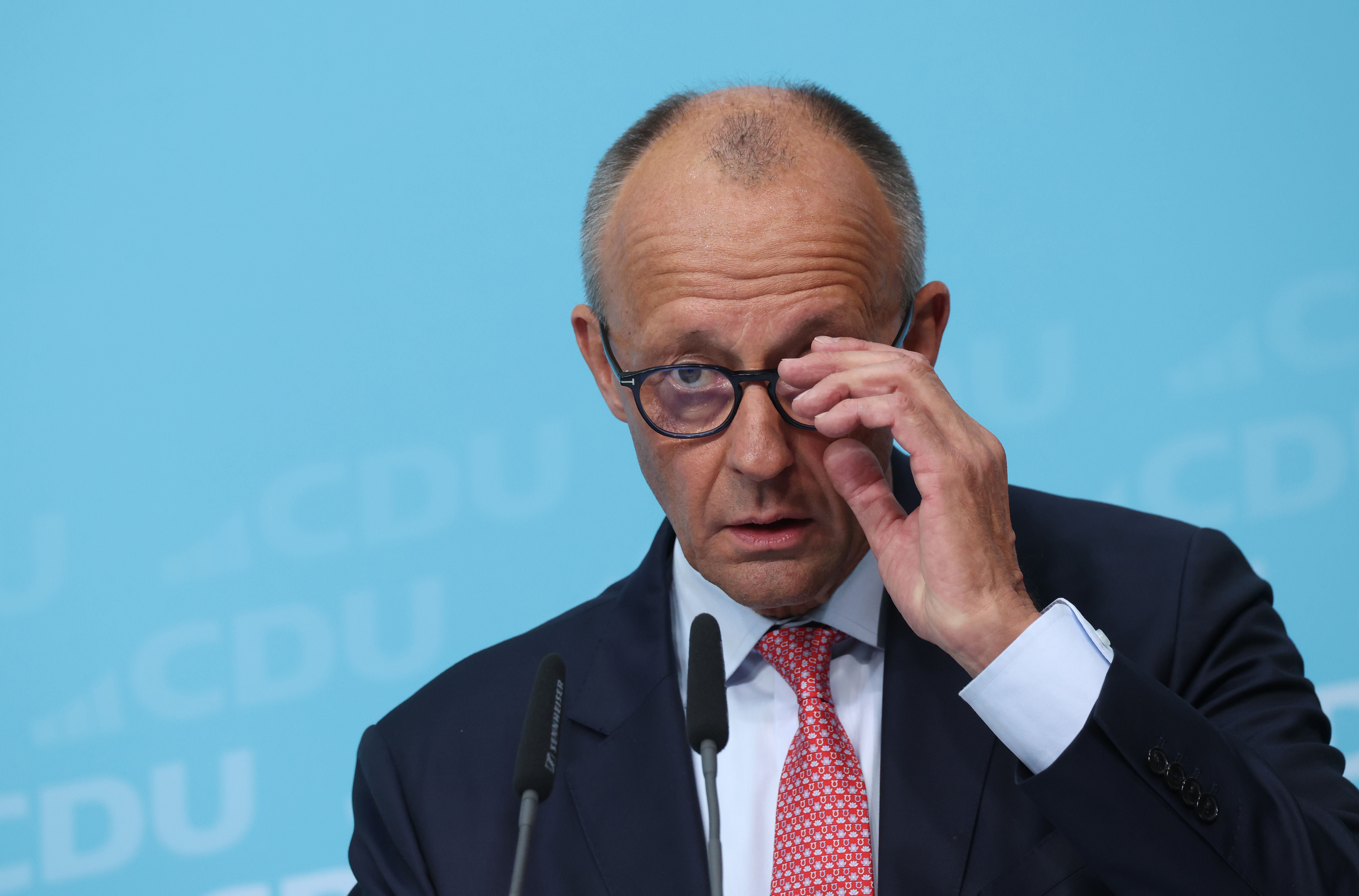 Ein Mann mit Brille und roter Krawatte spricht bei einer CDU-Veranstaltung am Mikrofon.