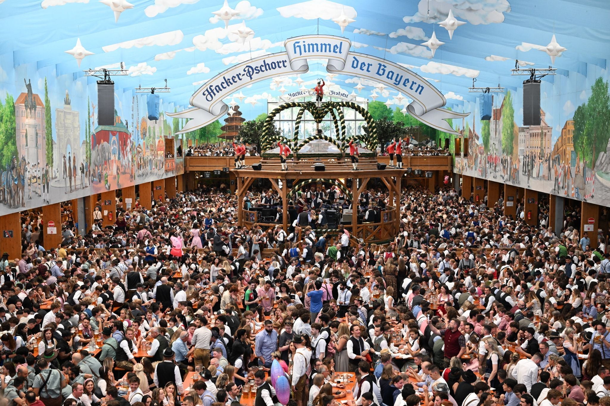 Menschenmenge im Hacker-Festzelt beim Oktoberfest, bunte Dekoration und festliche Atmosphäre.