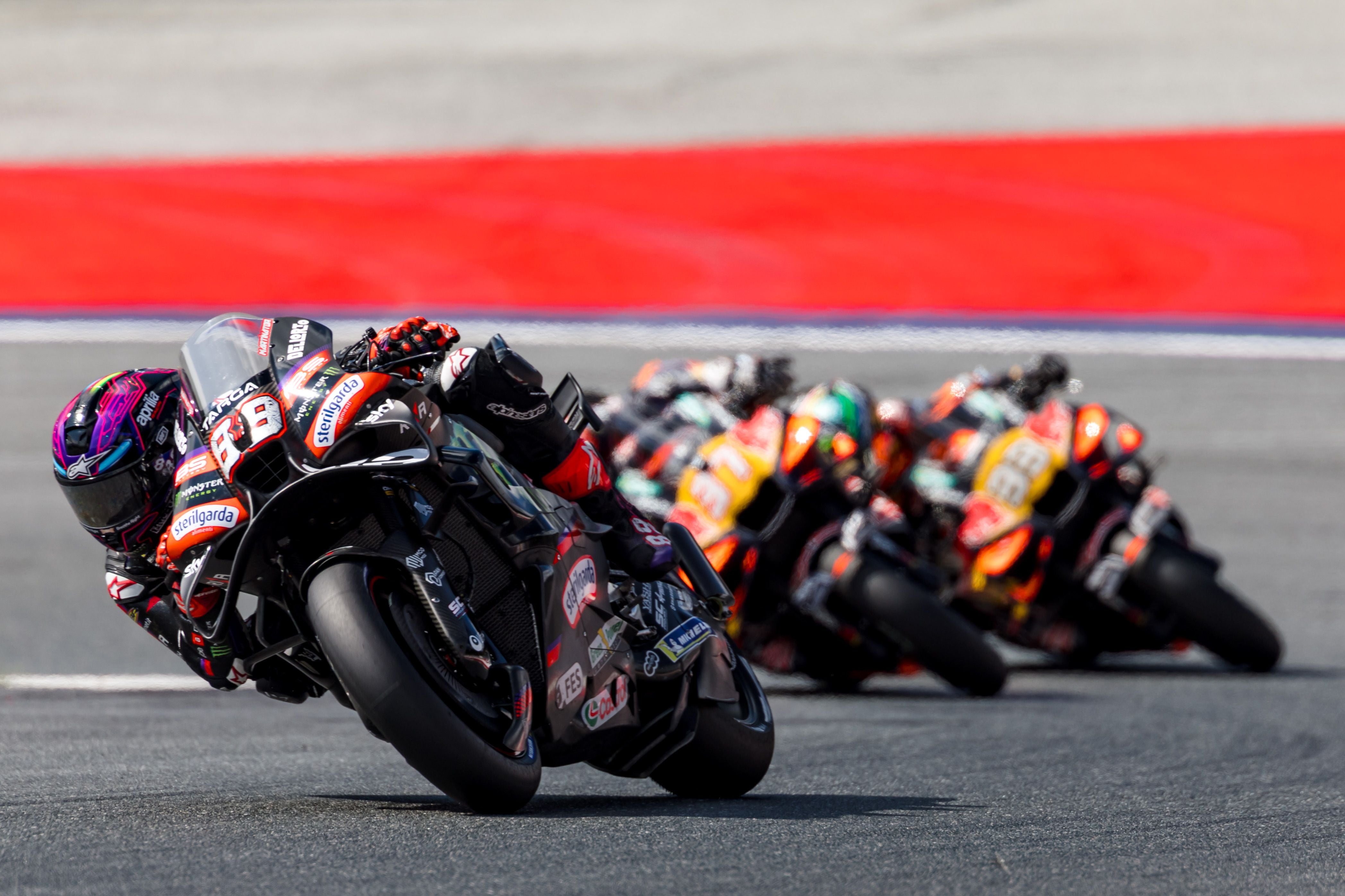Mehrere Motorradfahrer legen sich bei einem MotoGP-Rennen in eine Kurve.