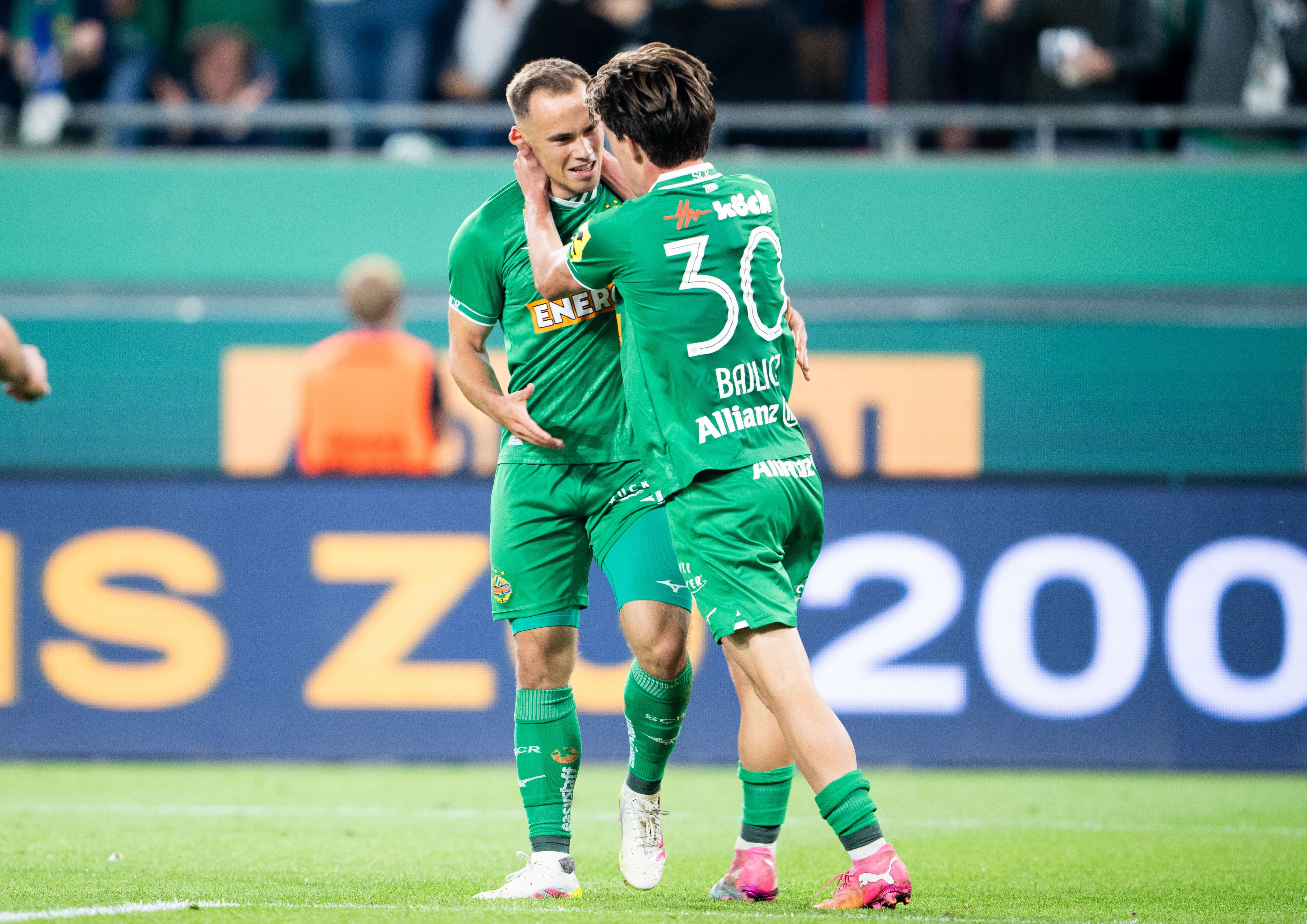 Zwei Rapid-Spieler jubeln nach einem Tor während eines Fußballspiels im Stadion.