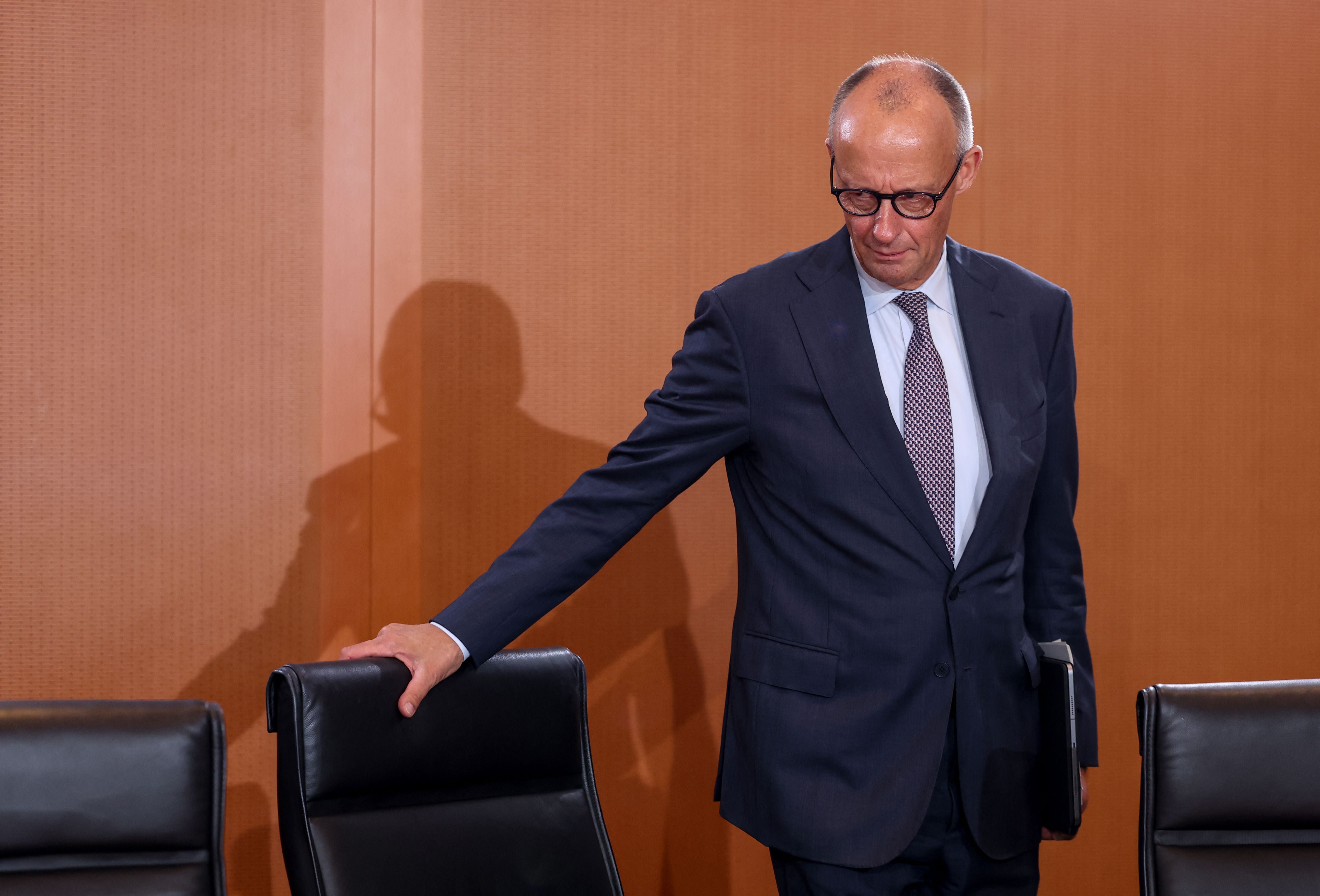 Ein Mann im Anzug betritt einen Konferenzraum und berührt einen Stuhl.