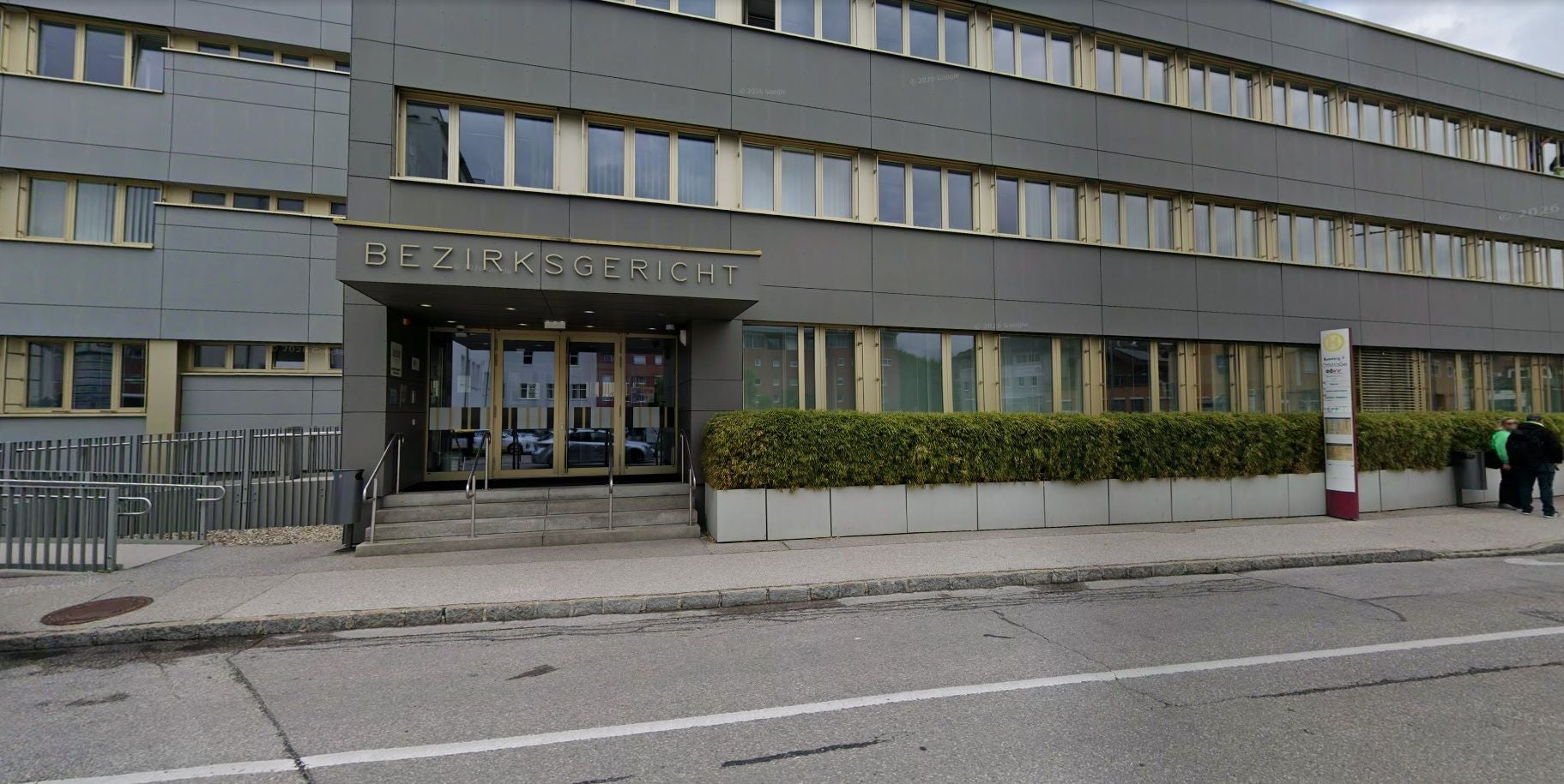 Eingang des Bezirksgerichts Vöcklabruck mit Glasdrehtür und moderner Fassade.