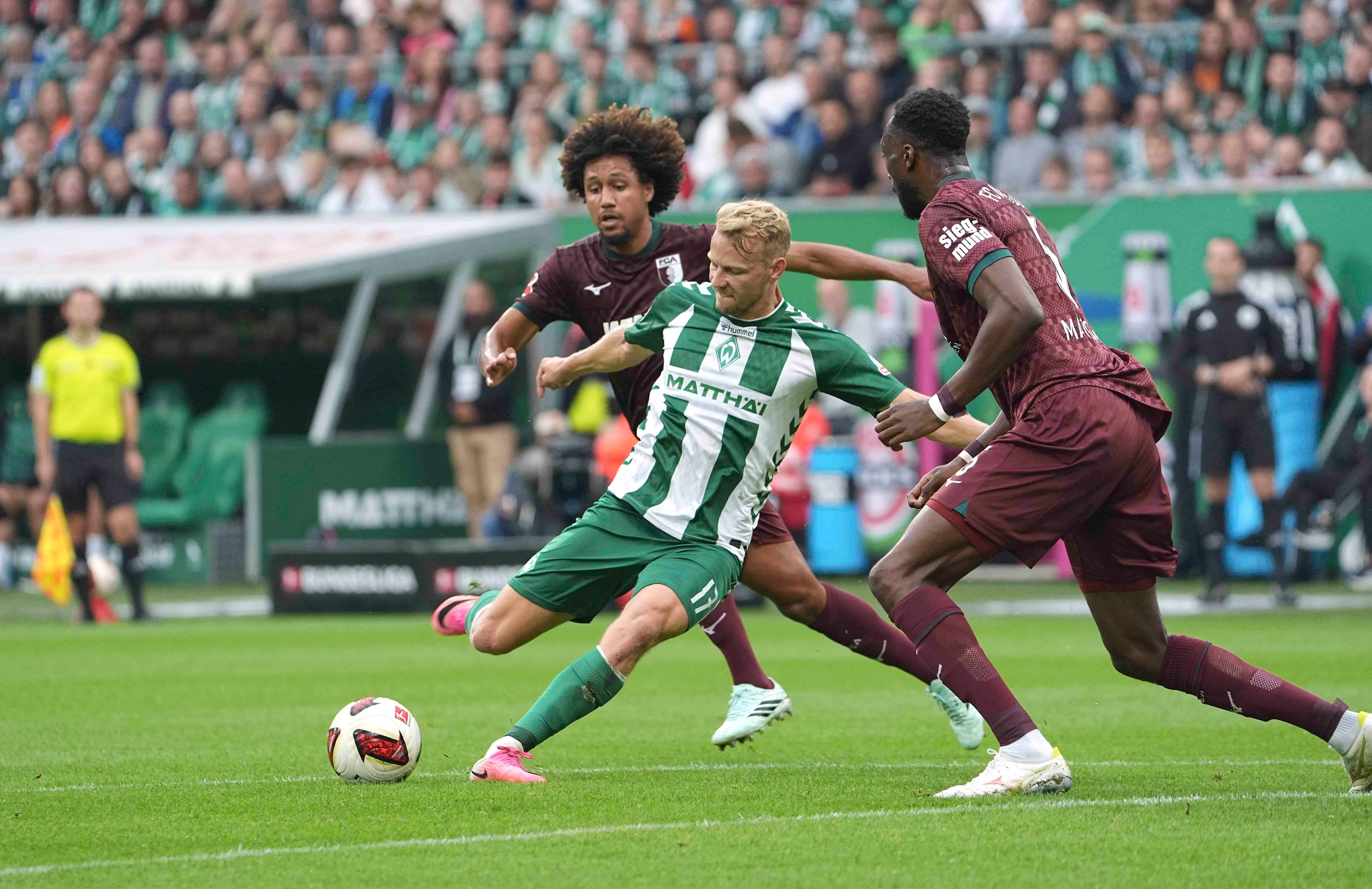 Ein Werder-Bremen-Spieler schießt aufs Tor, zwei Augsburger verteidigen im Strafraum.