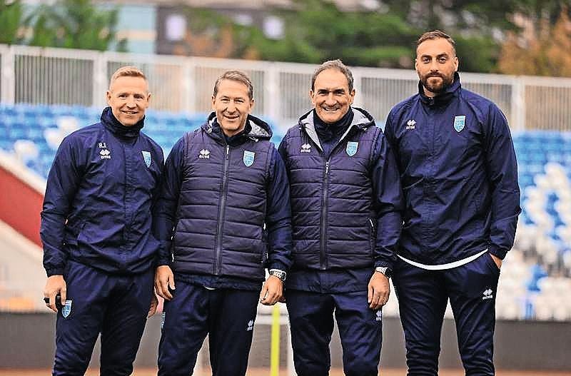 Das Trainerdienst-Quartett des Kosovo mit Robert Ibertsberger, Franco Foda, Thomas Kristl und Atdhe Nuhiu steht lächelnd in blauer Trainingskleidung nebeneinander.